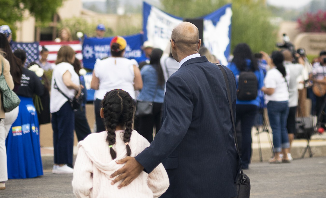 Man and child looking at a protest.