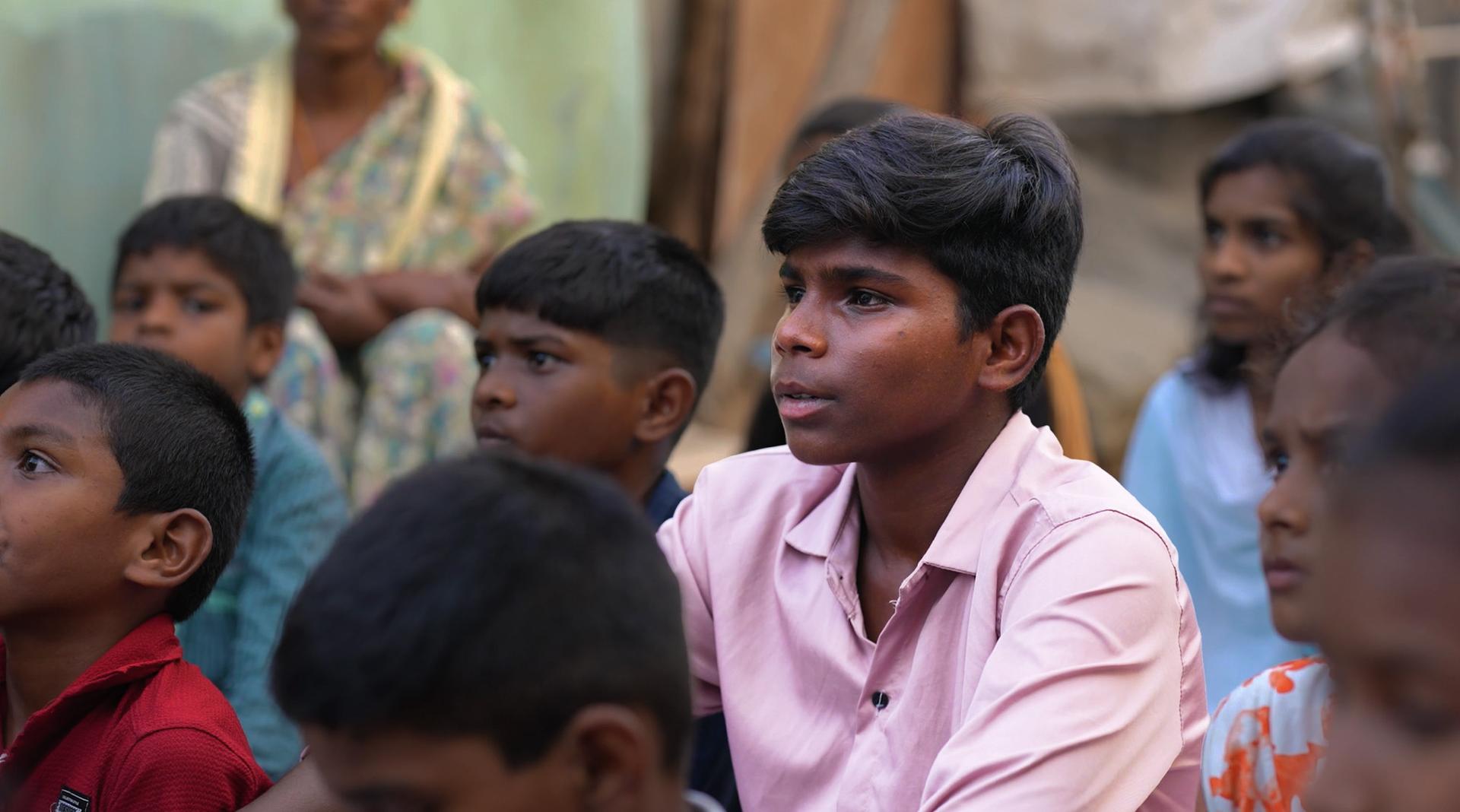 a group of Indian children sitting together facing one direction. one boy stands out that's distinguished as Jaivant.