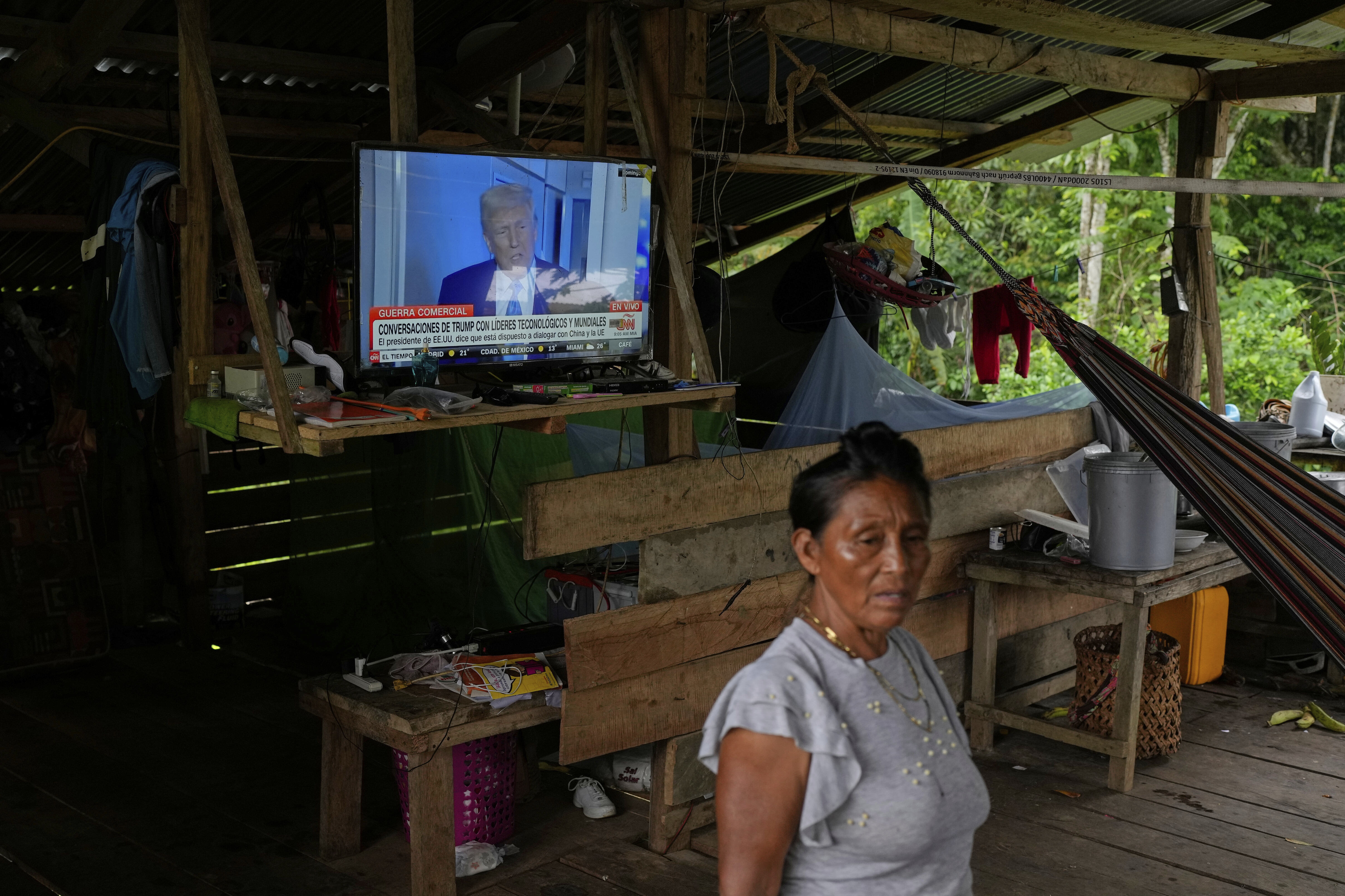 A woman stands at her home in Villa Caleta where she has the news on showing U.S. President Donald Trump on April 7. (AP Photo/Matias Delacroix)