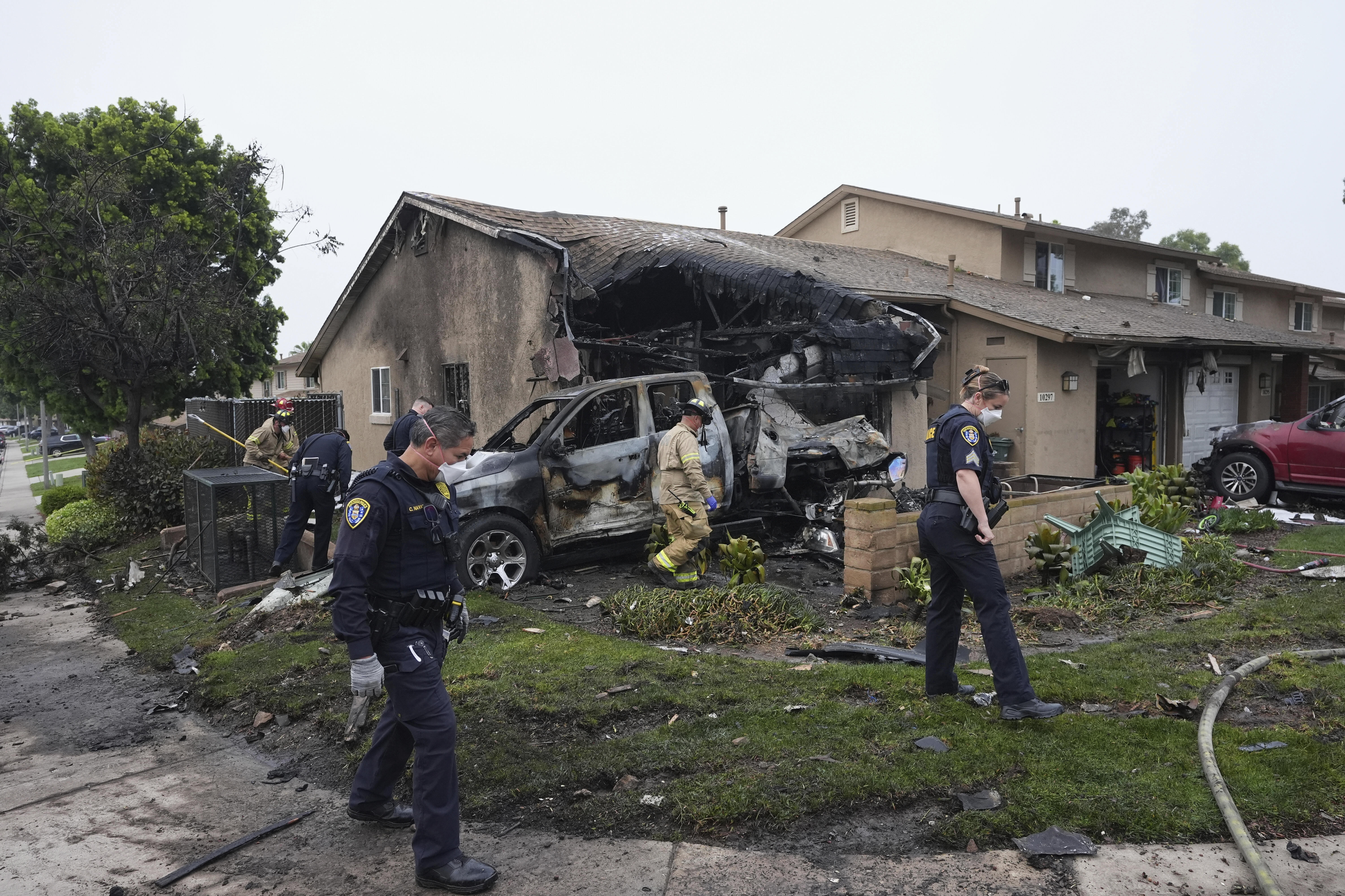 Authorities work the scene where a small plane crashed into a San Diego neighborhood, setting several homes on fire and forcing evacuations along several blocks early Thursday. (AP Photo/Gregory Bull).