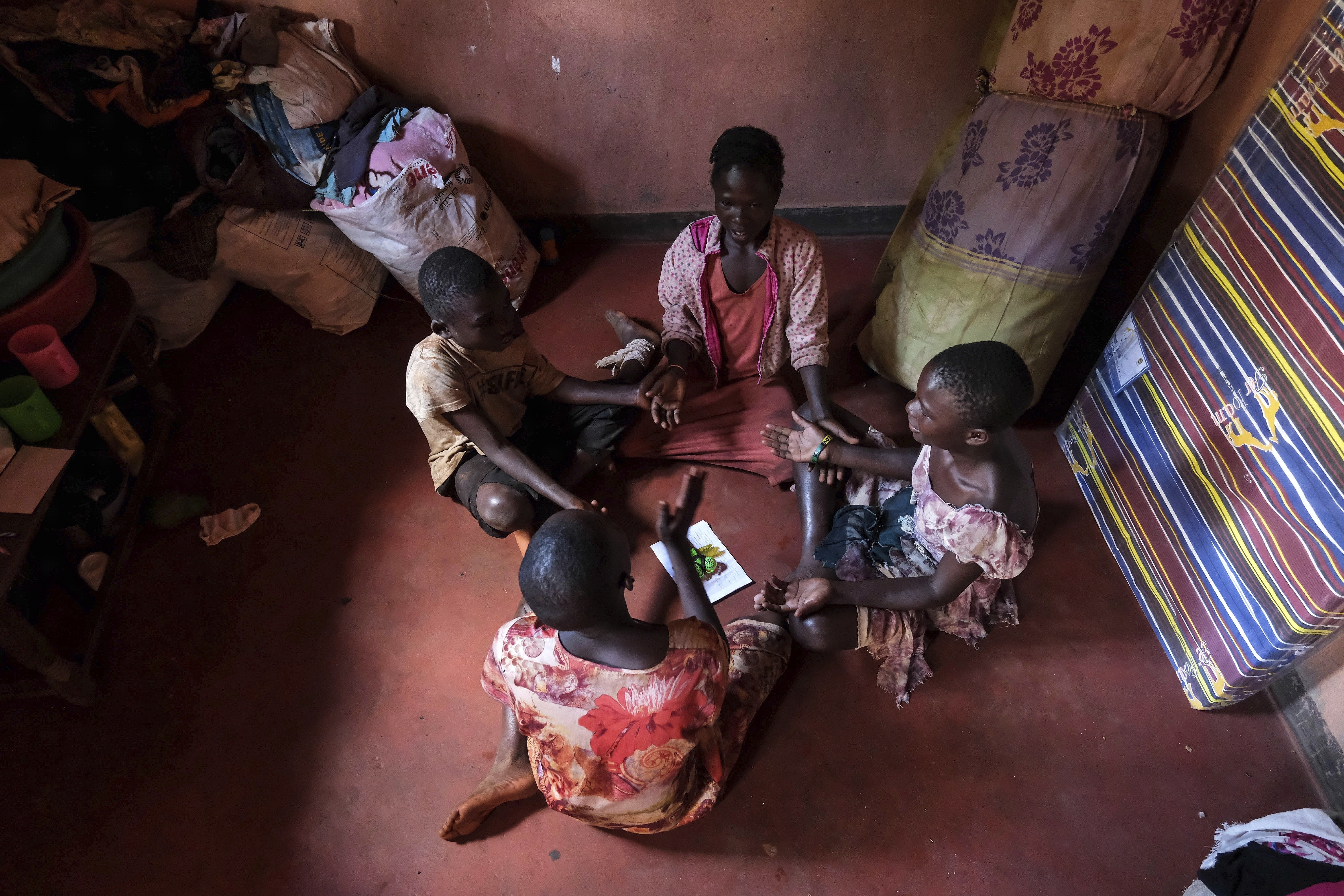 Children of Simon Tigawalana play while sitting on a clay-based earthen floor made by EarthEnable on May 16 in Jinja, Uganda. (AP Photo/Hajarah Nalwadda).