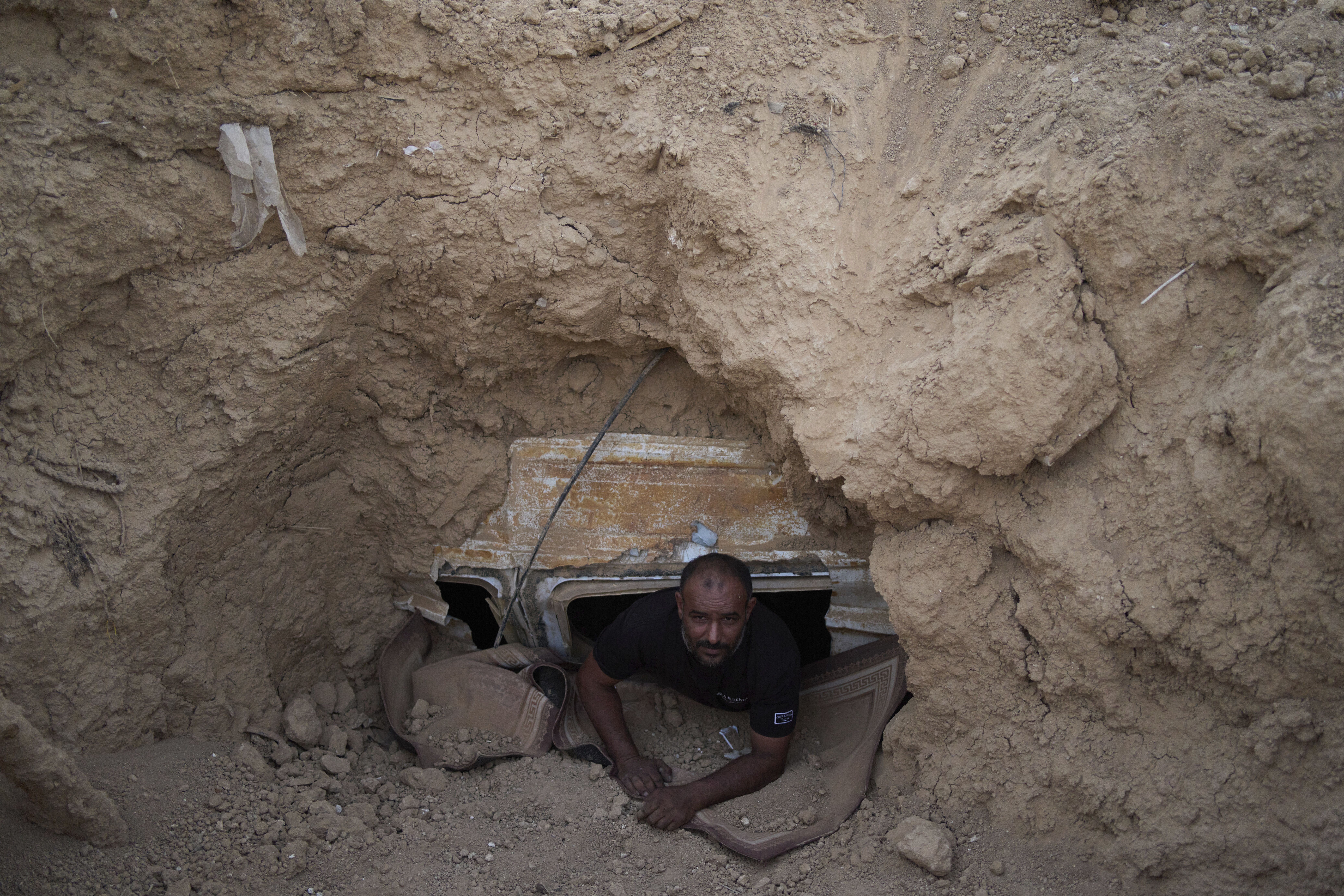 Ahmad Abu Ganima poses for a portrait in the window of the minibus buried in the earth, a makeshift bomb shelter his family uses in Khashem Zaneh, an unrecognized Bedouin village in the Negev Desert, southern Israel on July 2. (AP Photo/Maya Alleruzzo).