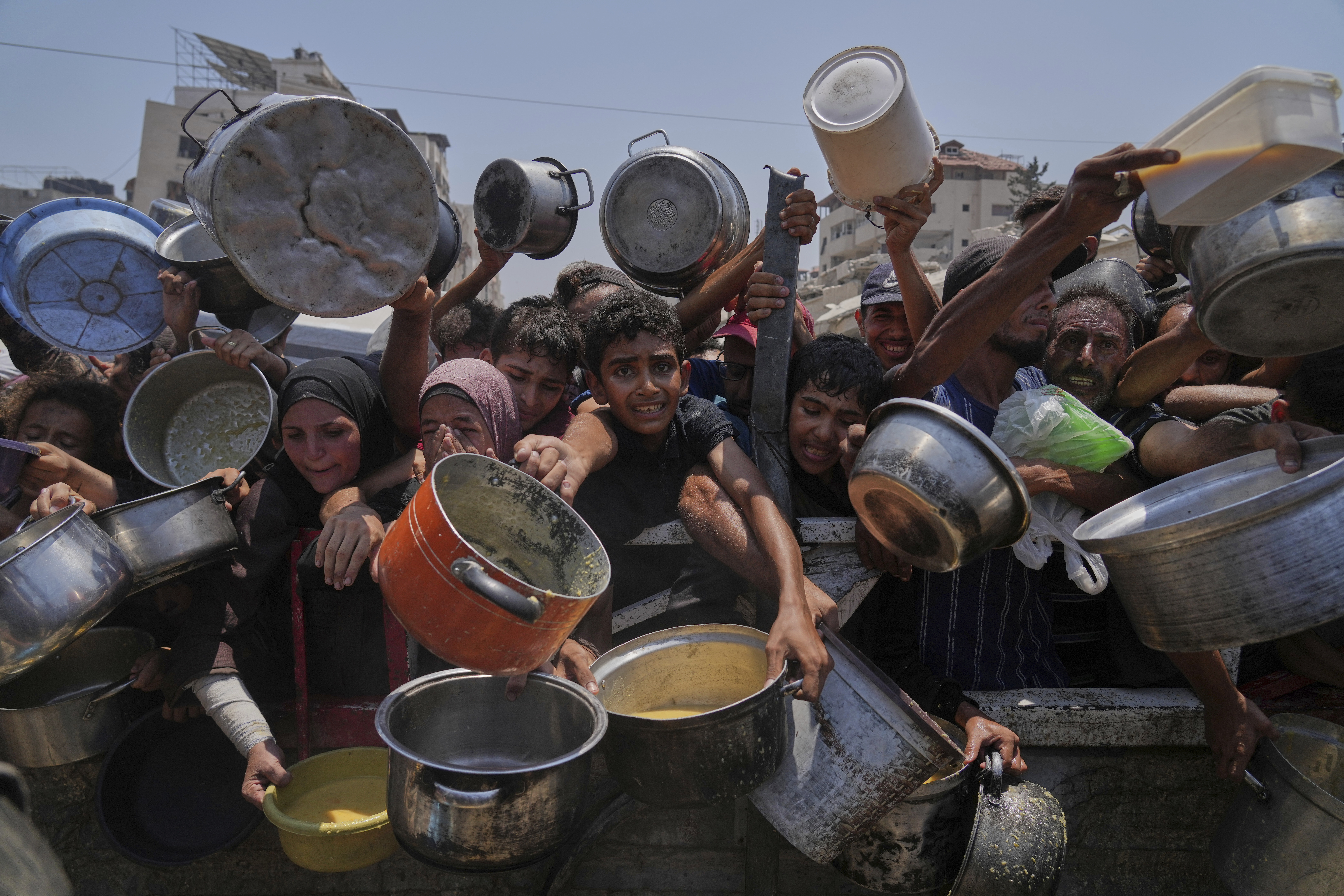 Palestinians struggle to get donated food at a community kitchen, in Gaza City, northern Gaza Strip, Saturday. (AP Photo/Abdel Kareem Hana)