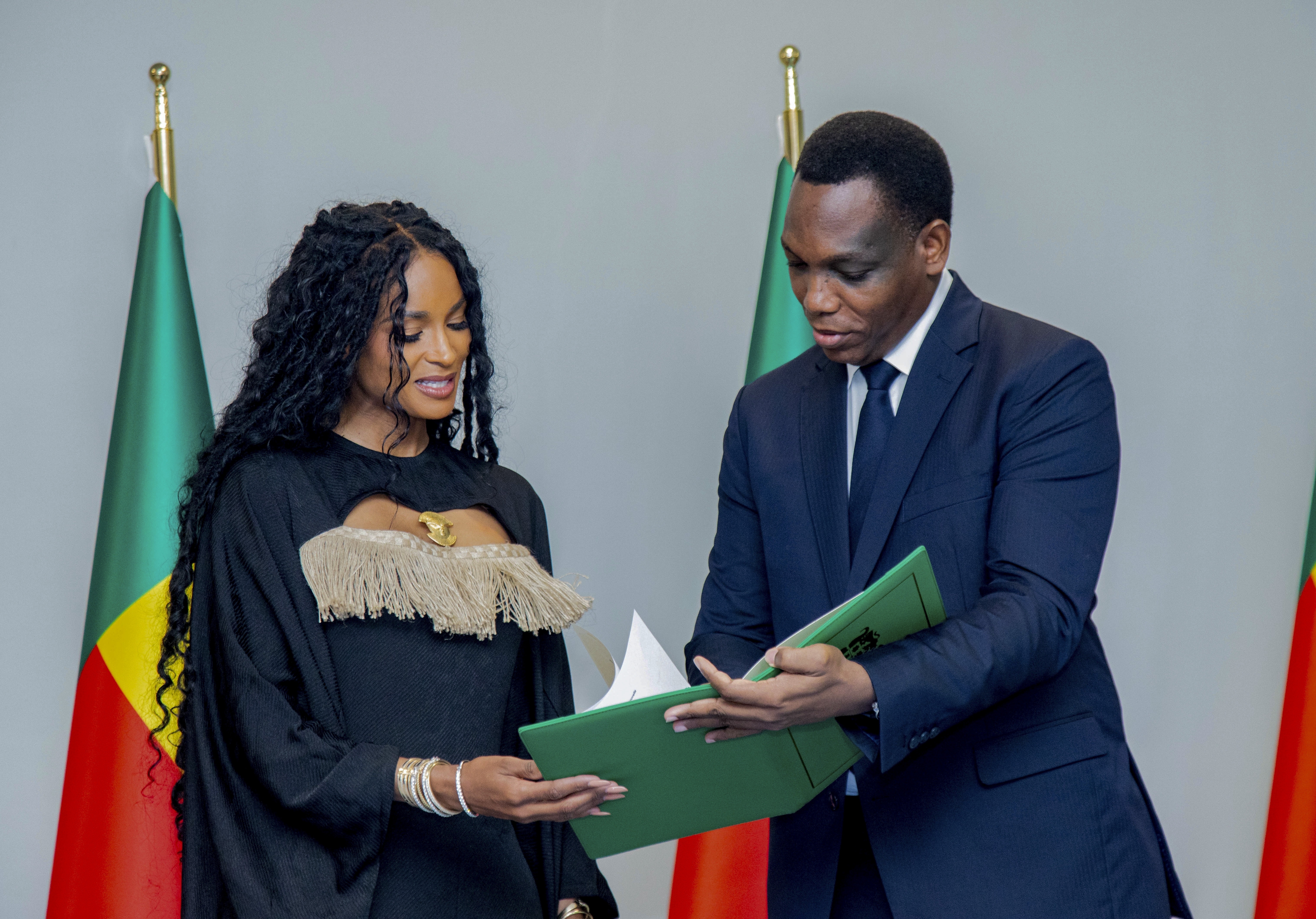 Yvon Detchenou, Benin's Minister of Justice and Legislation, right, presents citizenship documents to singer Ciara at a ceremony in Cotonou, Benin, Saturday. (Benin Presidency via AP)