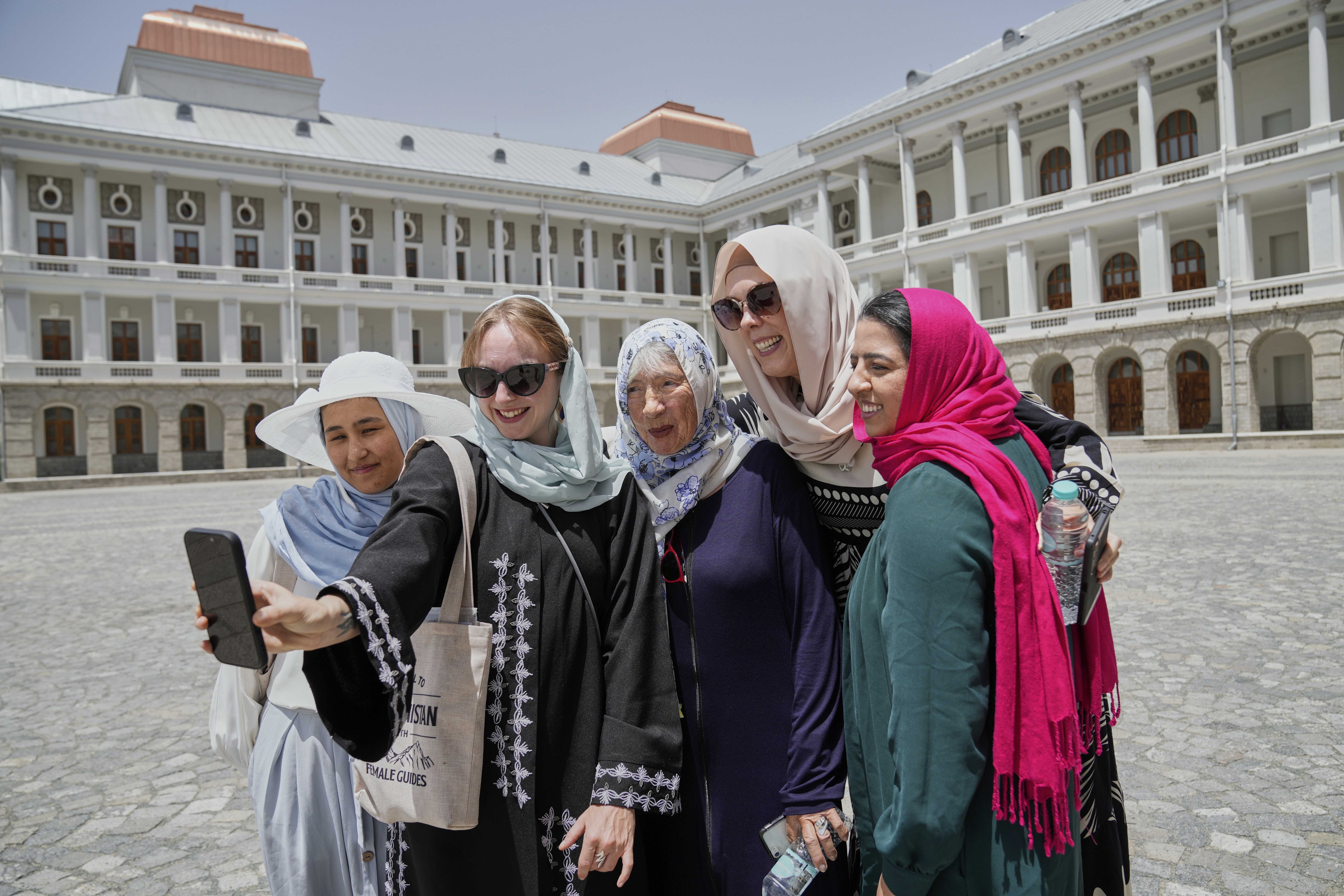 Zoe Stephens, 31, from Britain, takes a selfie with other foreign, female tourists and Maryam, a local trainee tour guide, at left, at Darul Aman Palace in Kabul, Afghanistan, Wednesday, May 28, 2025. (AP Photo/Ebrahim Noroozi)