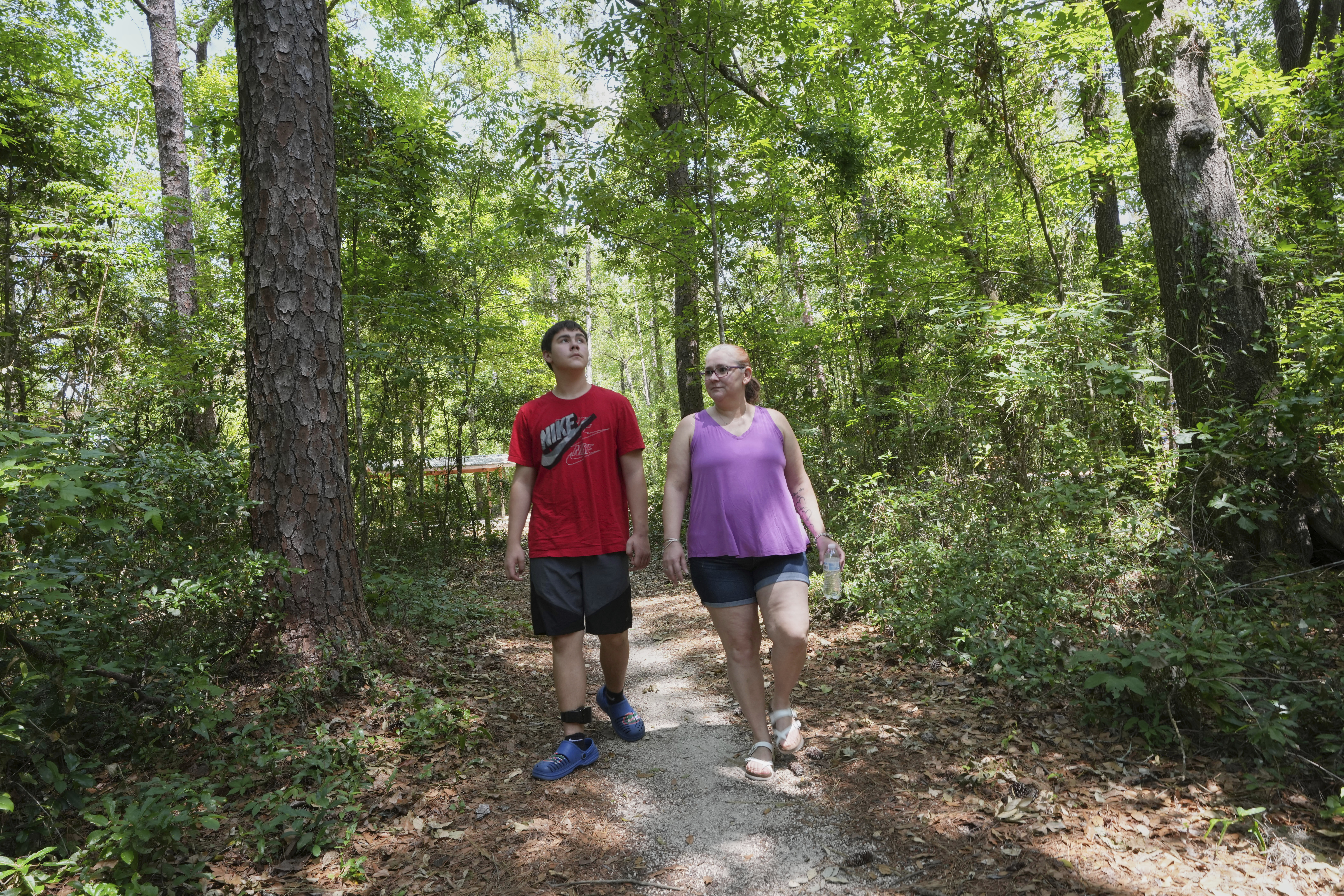 Cayden and his mother Robyn Gillespie walk in a county park Saturday, April 26, 2025, in Gainesville, Fla. (AP Photo/Marta Lavandier)