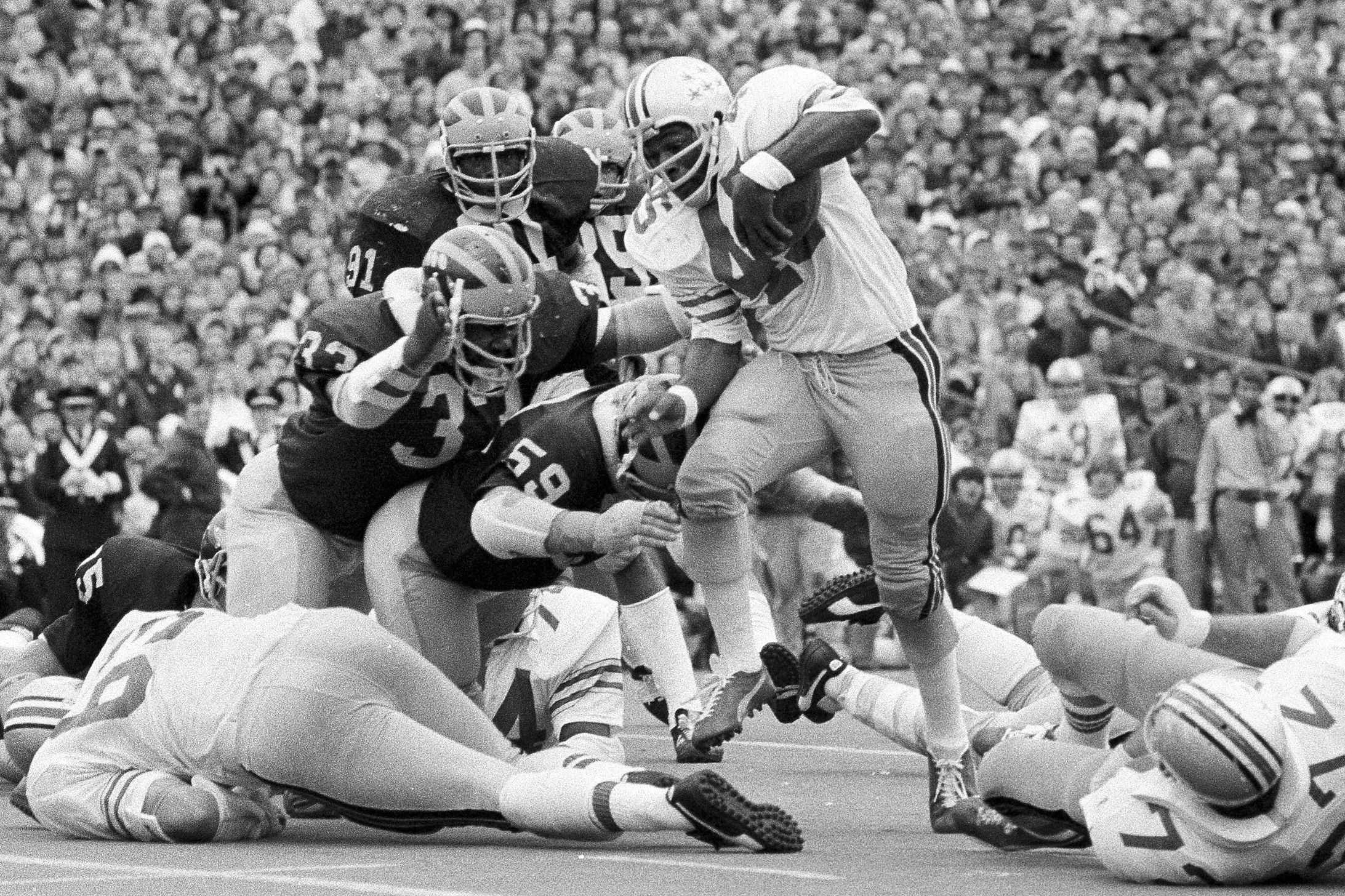 Ohio State's Archie Griffin picks up some of his game-high 163 yards against Michigan during an NCAA college football game in Ann Arbor, Mich., as Michigan's Walt Williamson (91), Carl Russ (33) and Steve Strinko (59) defend. (AP Photo/File)