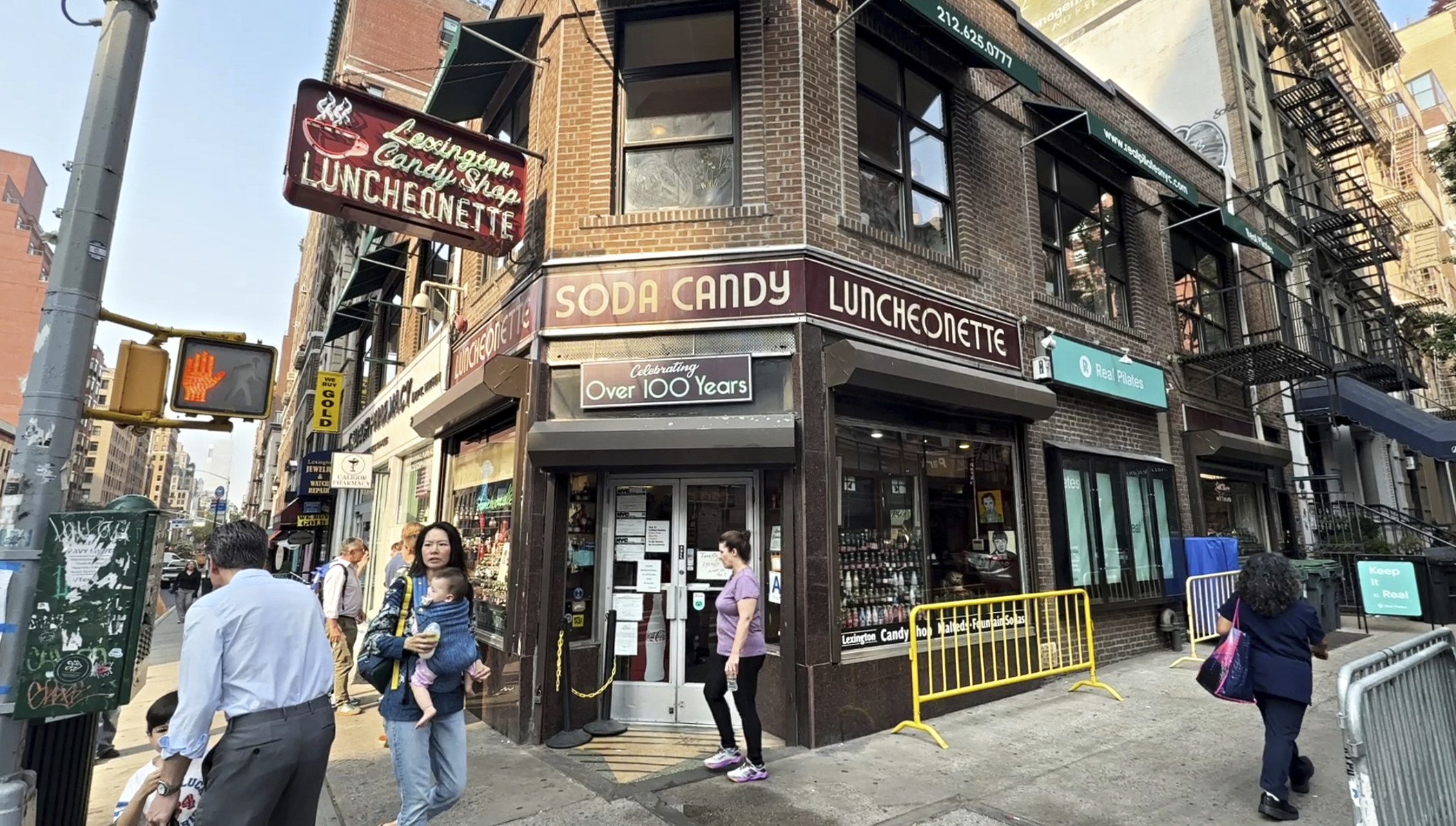 Pedestrians walk outside the Lexington Avenue Candy Shop Luncheonette in New York on Aug. 7. (AP Photo/Guido Neira).