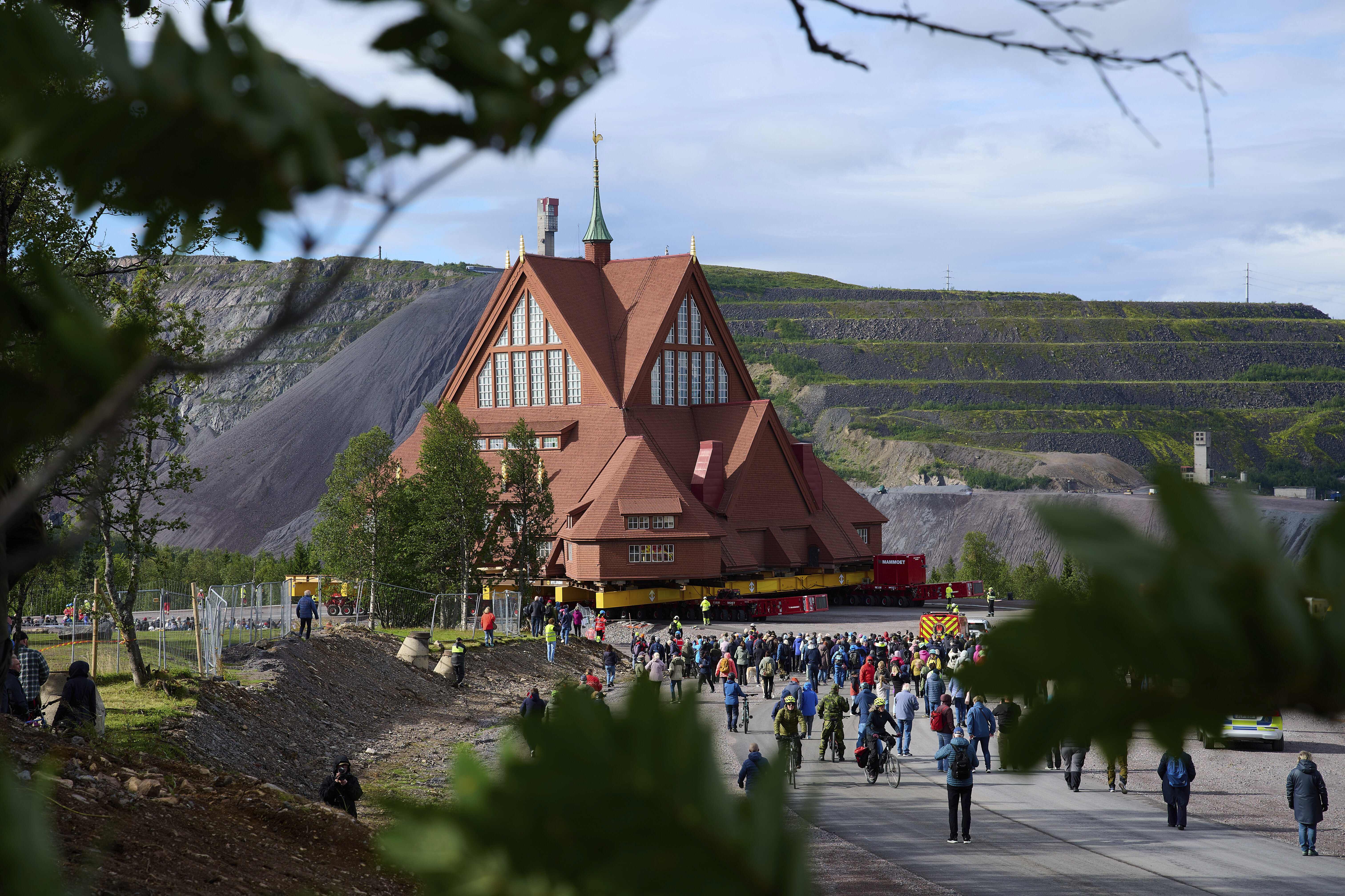 People gather outside the Kiruna Church, a Sami style wooden Swedish Lutheran church in Kiruna, Sweden, on Tuesday during its move along a 5-kilometer (3-mile) route east to a new city center as part of the town's relocation. (AP Photo/Malin Haarala)