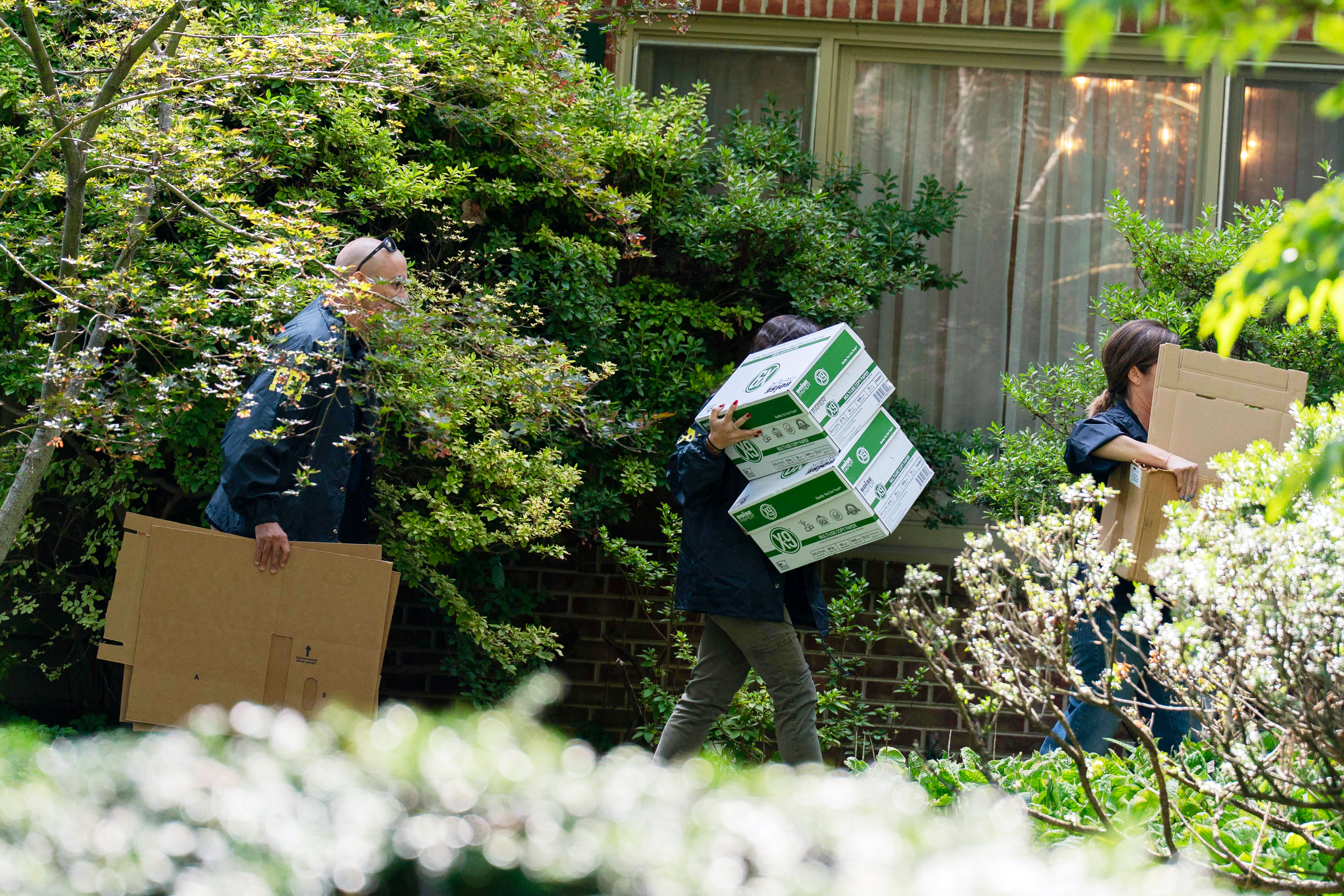 FBI agents carry empty boxes to former national security adviser John Bolton's house Friday in Bethesda, Md. (AP Photo/Jose Luis Magana).