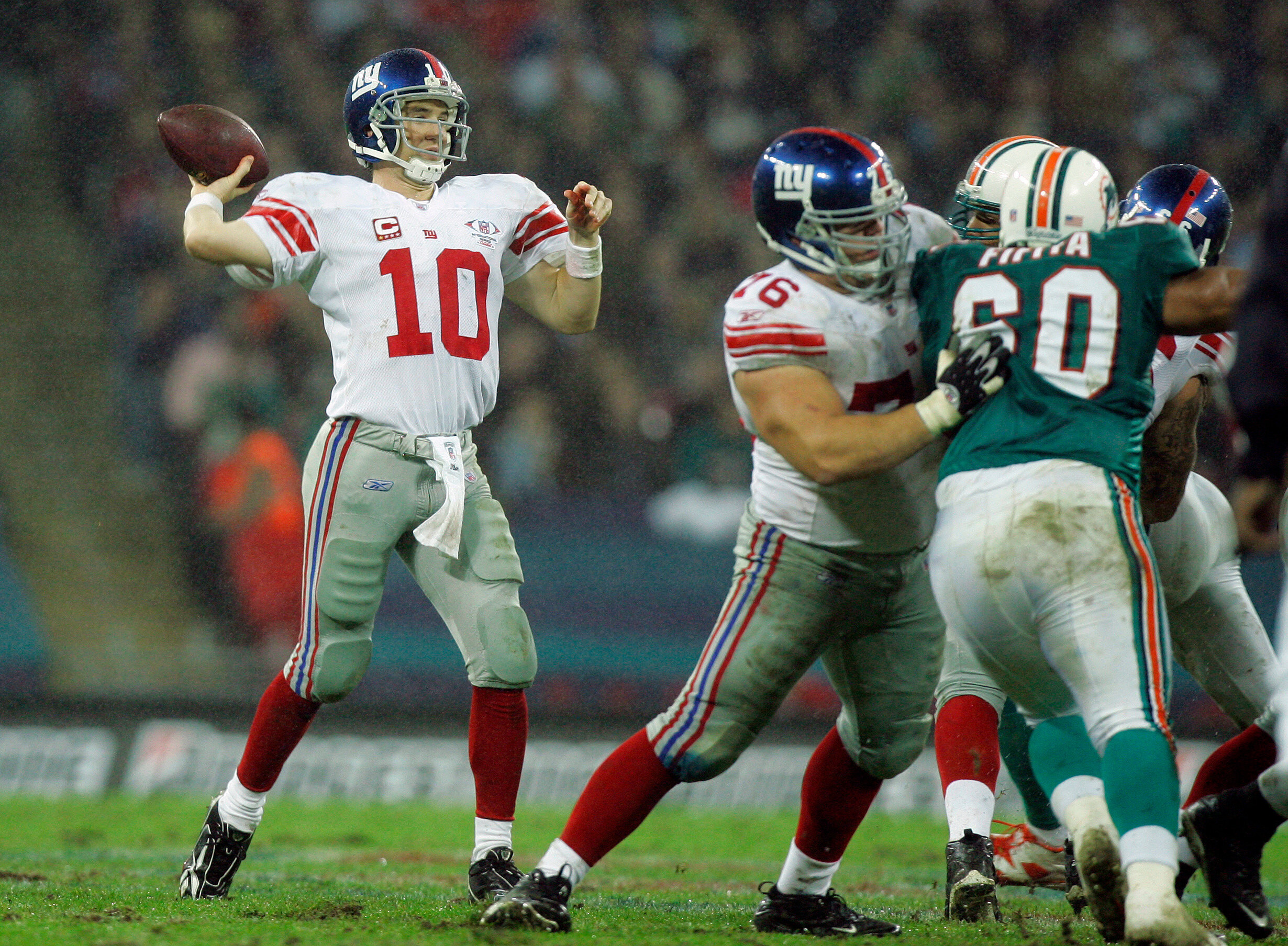 FILE - New York Giants' Eli Manning quarter back (10) throws the ball whilst Miami Dolphins, Stiveni Fifita (60 ) is held back during the second quarter of their NFL football game at Wembley Stadium in London, Oct. 28, 2007. (AP Photo/Kirsty Wigglesworth, file)