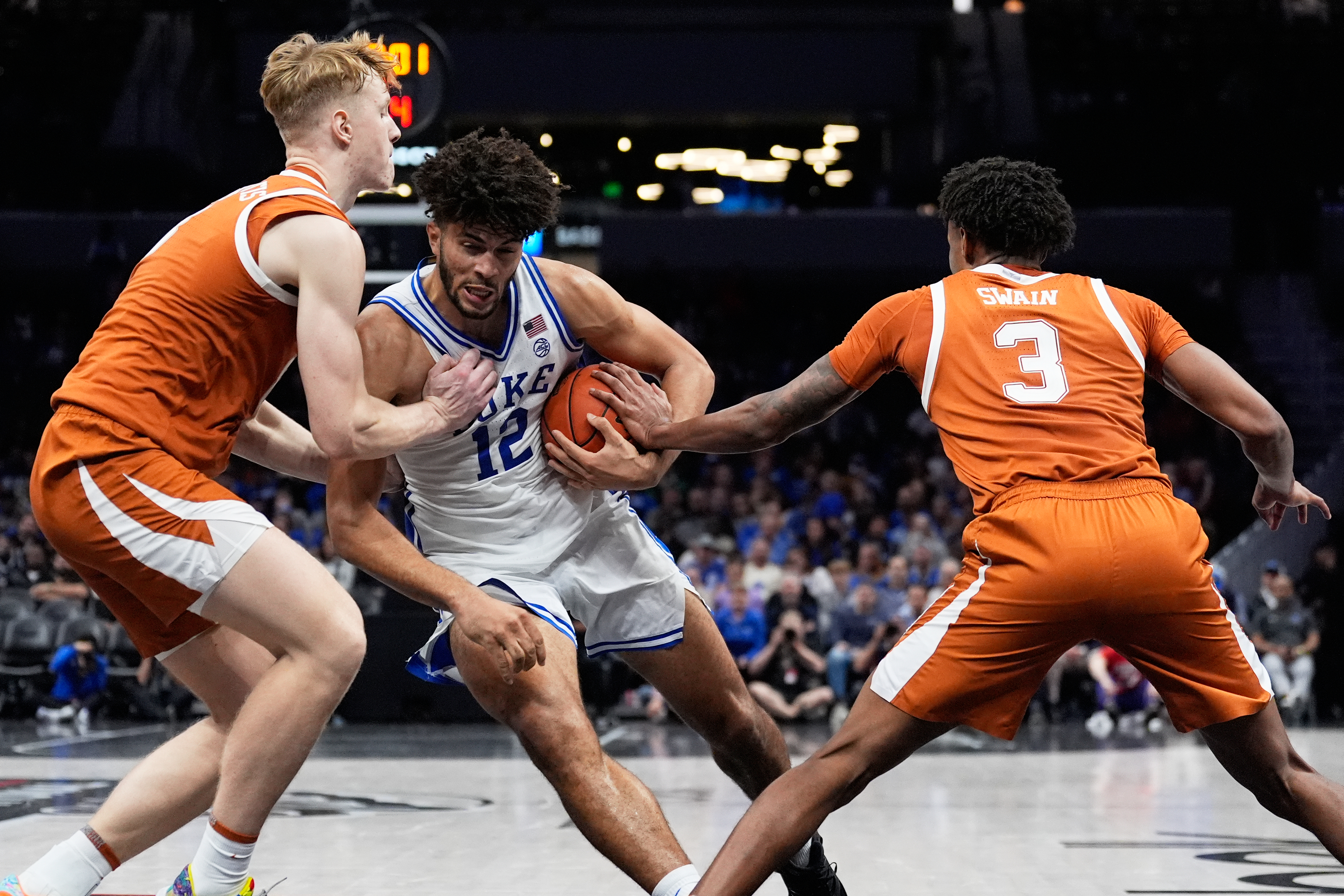 Duke forward Cameron Boozer drives to the basket between Texas center Matas Vokietaitis, left, and forward Dailyn Swain during the second half of an NCAA college basketball game, Tuesday, Nov. 4, 2025, in Charlotte, N.C. (AP Photo/Chris Carlson)