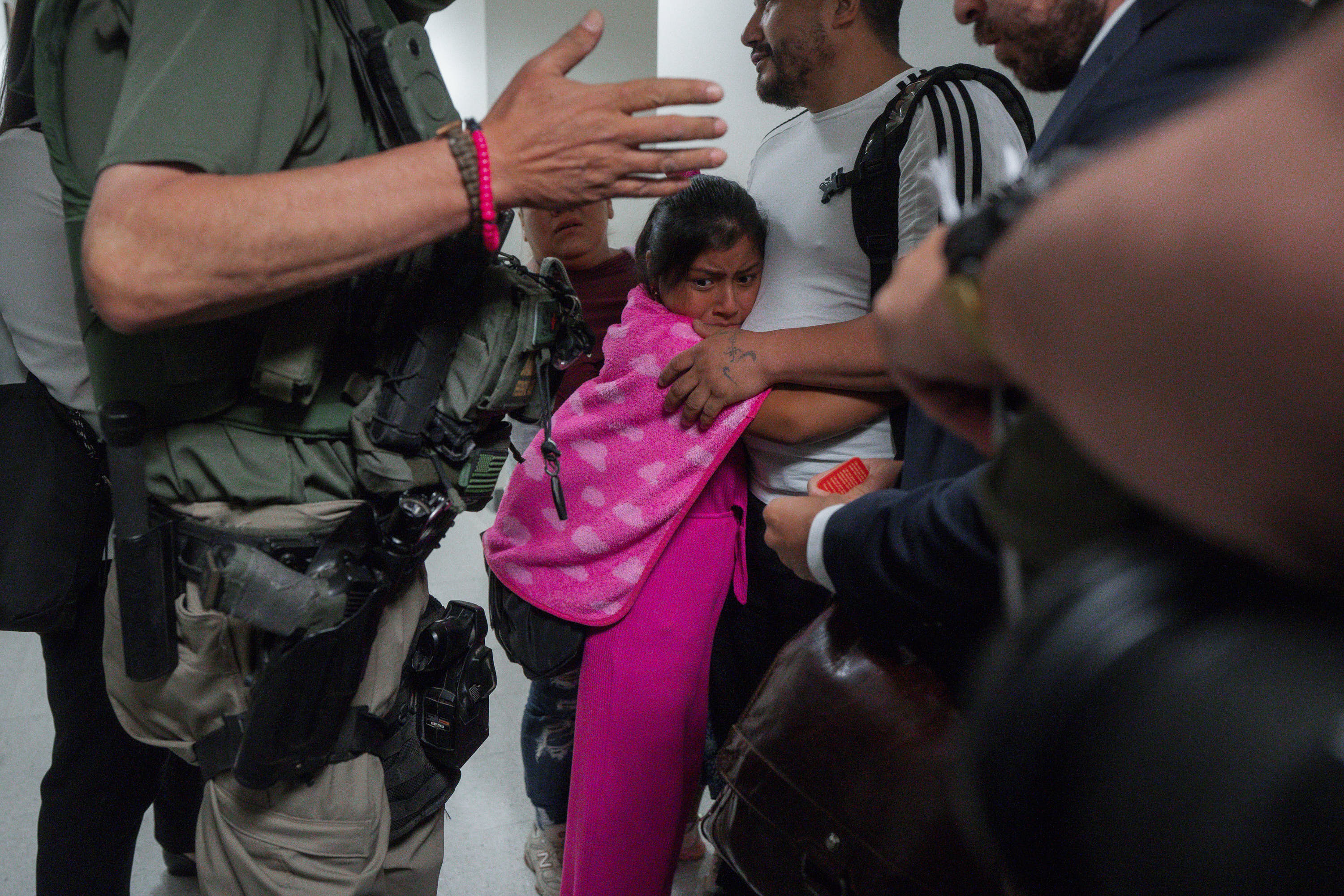 A girl clings to her father as he is detained by federal agents outside an immigration court in lower Manhattan.
