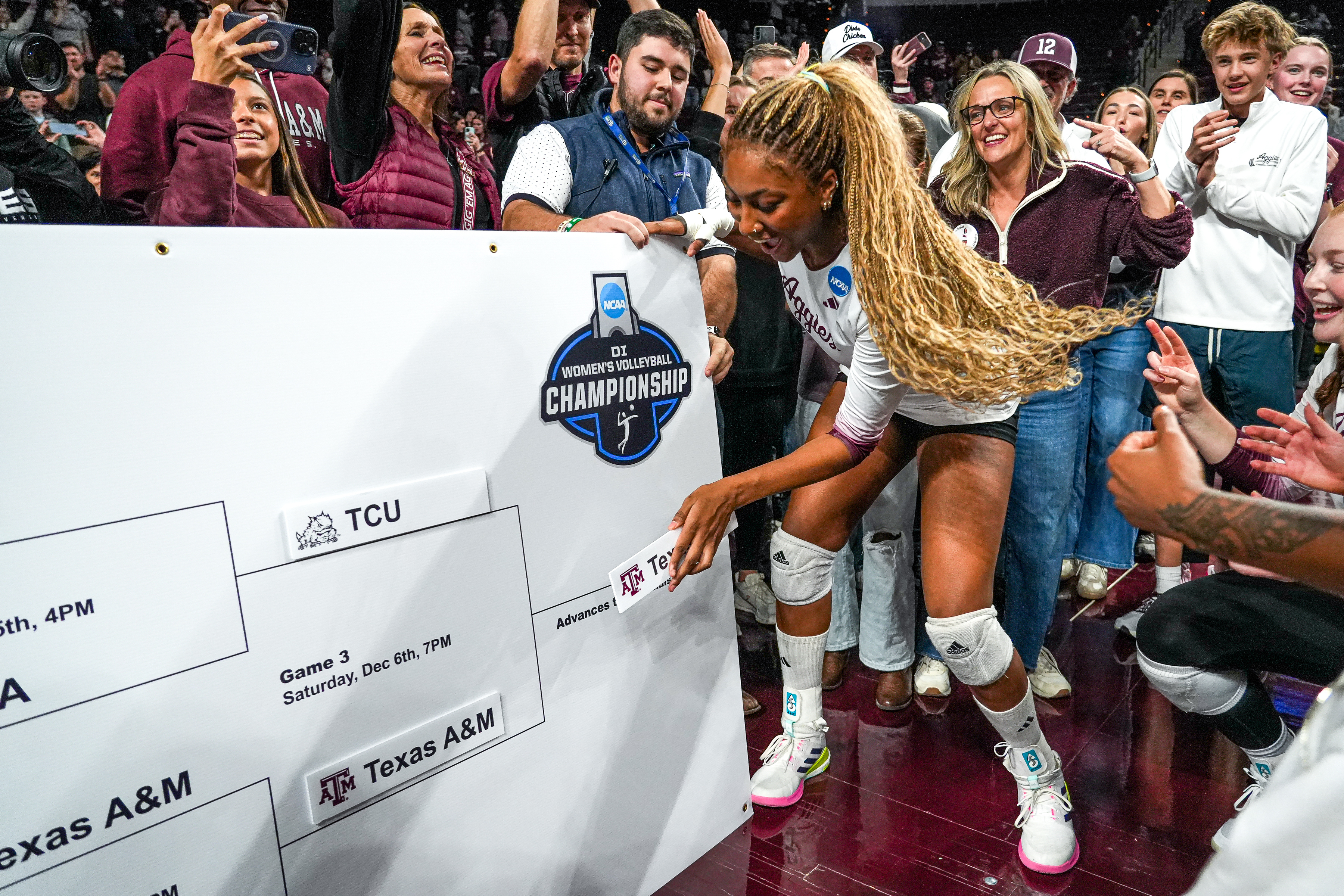 Texas A&M middle blocker Morgan Perkins, center, places the Texas A&M logo on an NCAA bracket after winning the NCAA Division I volleyball playoff game against TCU, Dec. 6, 2025, in College Station, Texas. (Aaron E. Martinez/Austin American-Statesman via AP, File)