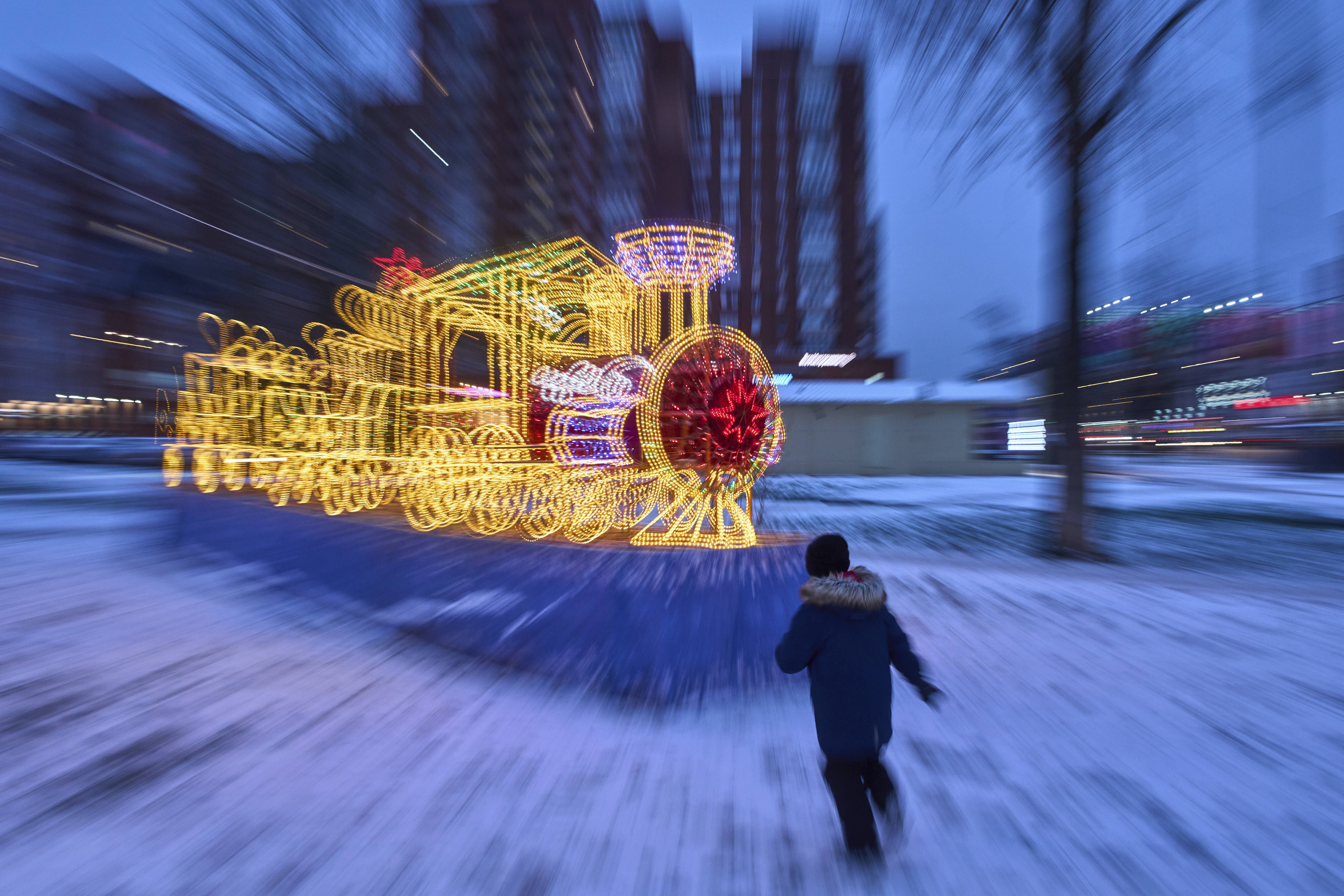 A boy runs toward a model train illuminated with holiday lights in St. Petersburg, Russia.