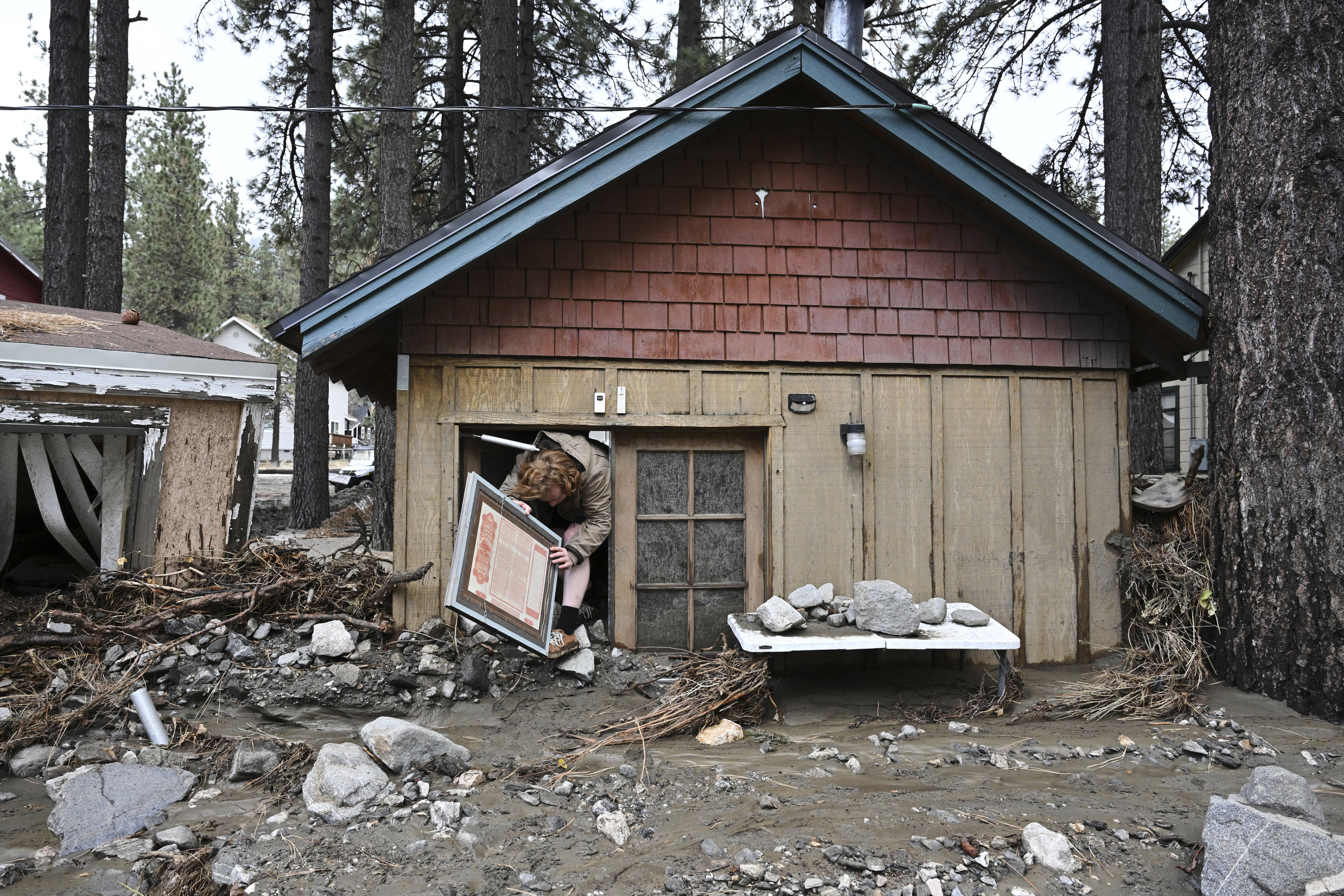 Davey Schneider recovers an item from his storm-damaged home in Wrightwood.