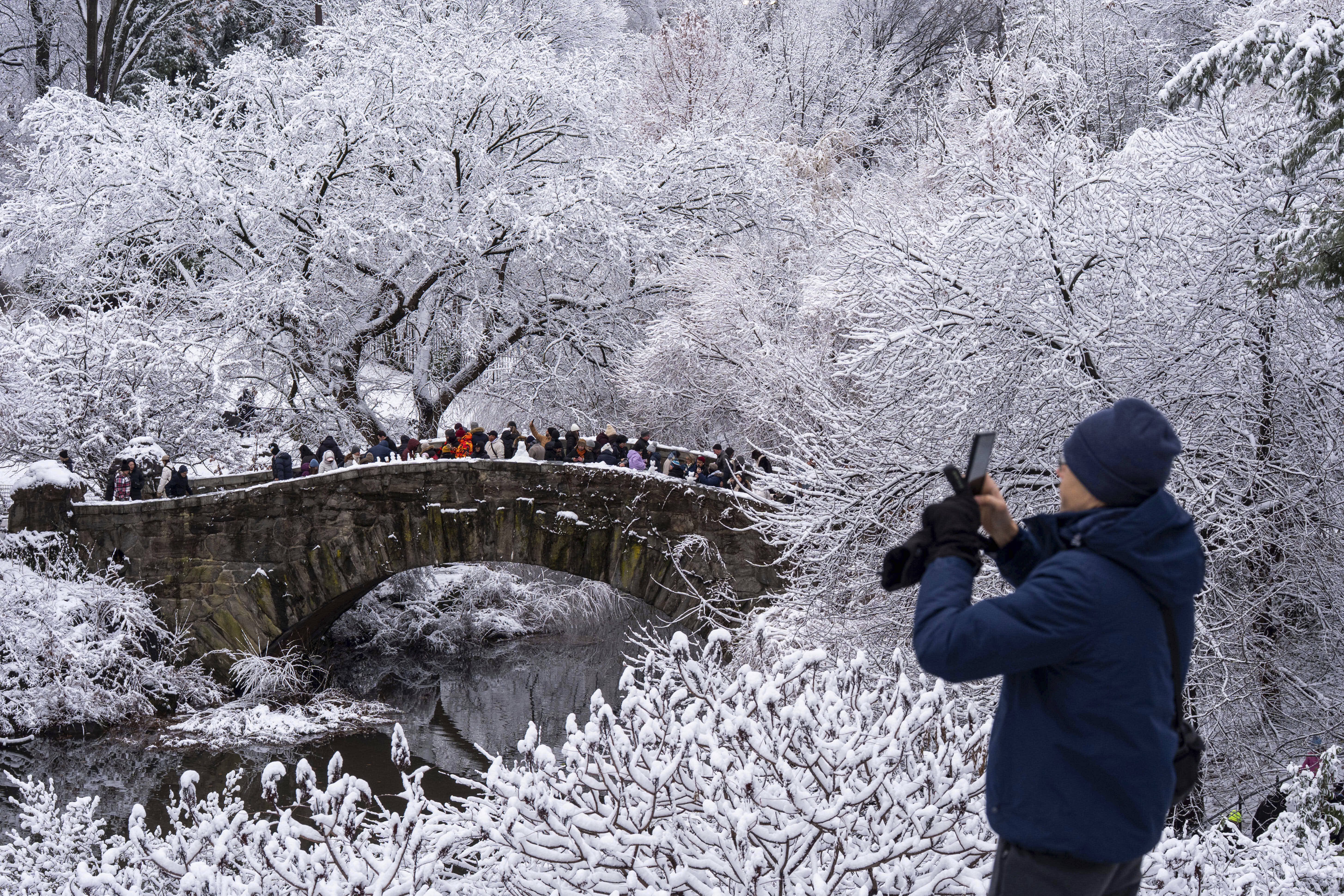 Tourists cross Gapstow Bridge in snow-covered Central Park in New York.