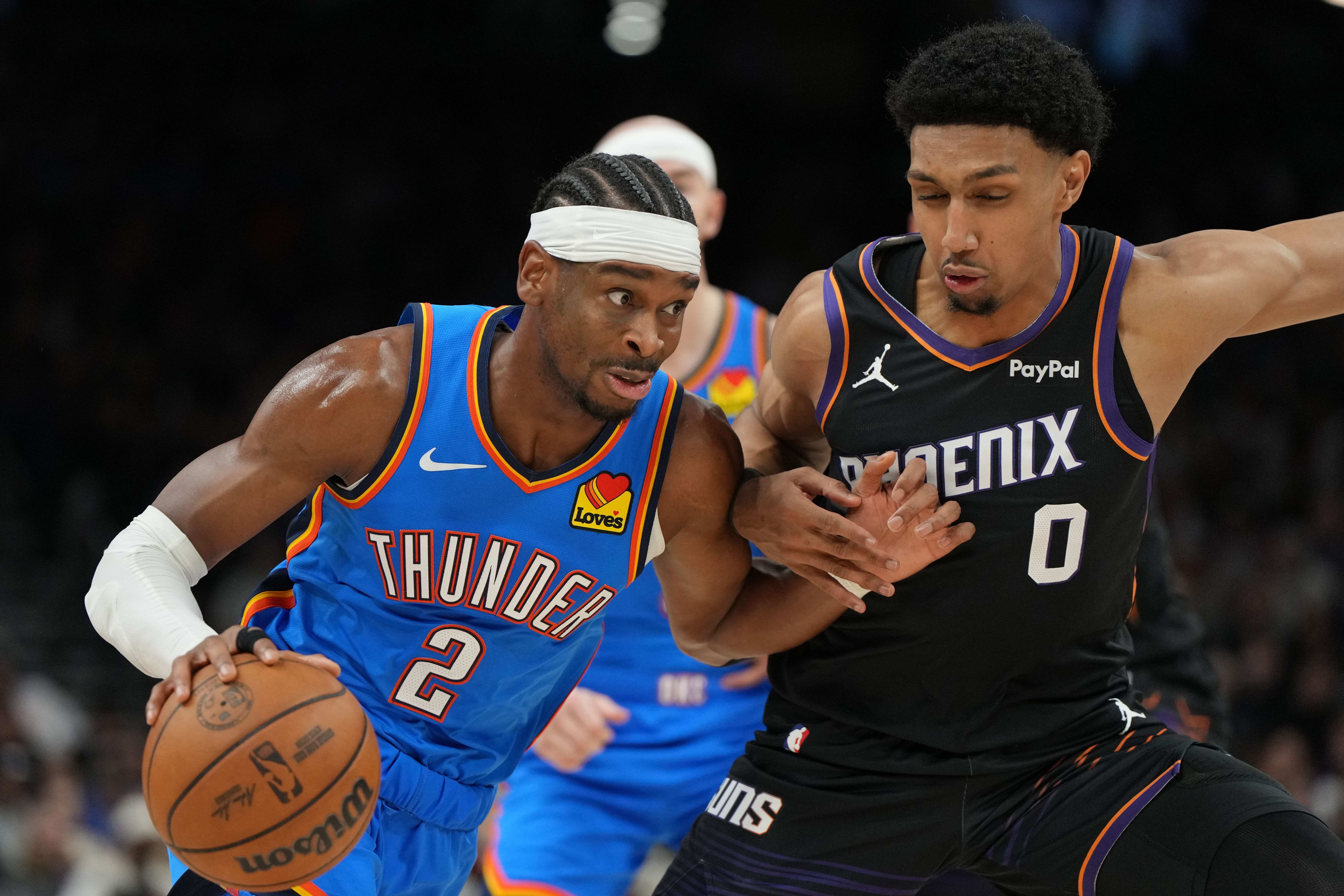Oklahoma City Thunder guard Shai Gilgeous-Alexander (2) drives on Phoenix Suns forward Ryan Dunn during the second half of an NBA basketball game, Sunday, Jan. 4, 2026, in Phoenix.