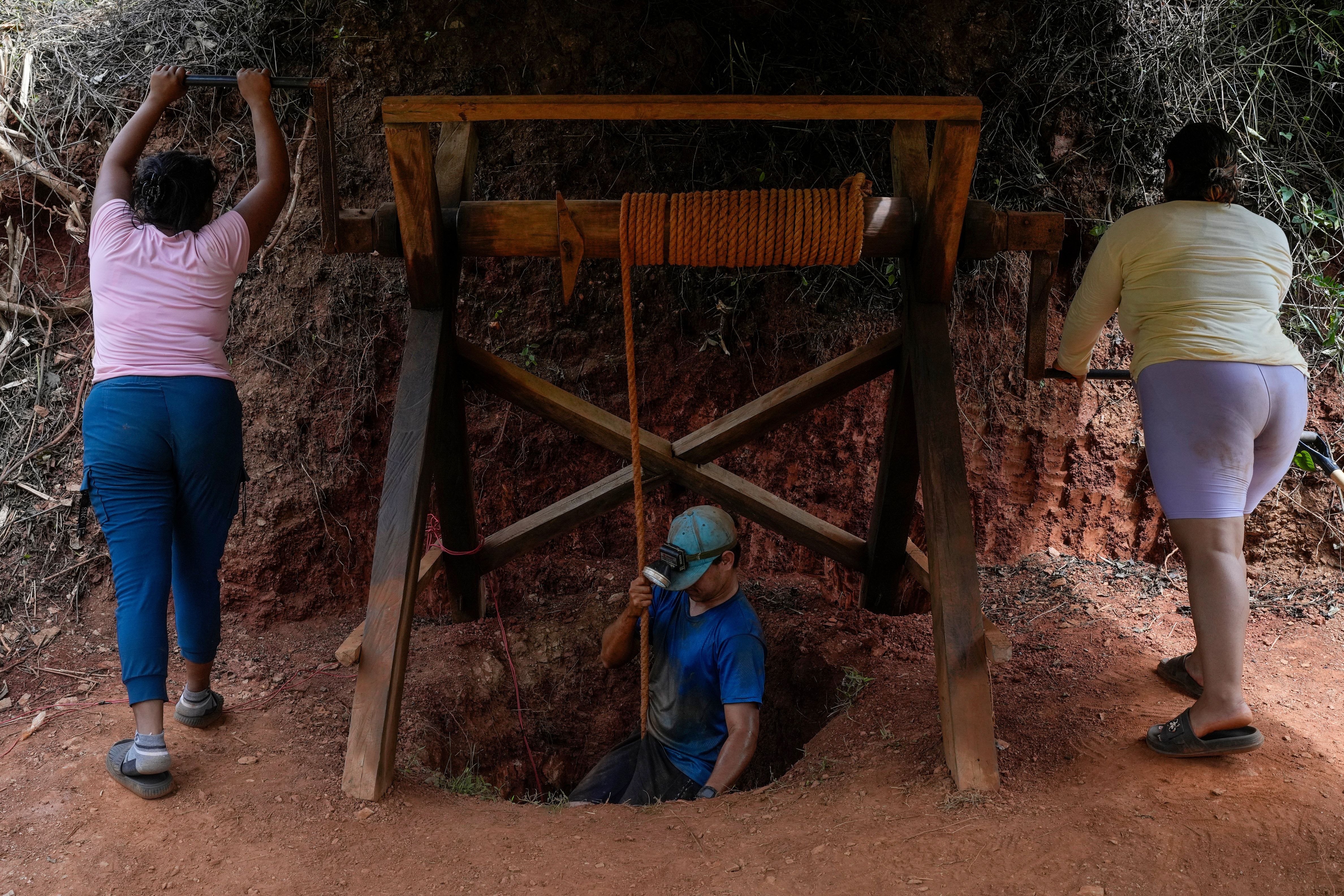 Women lower a miner into a gold mine pit in Venezuela