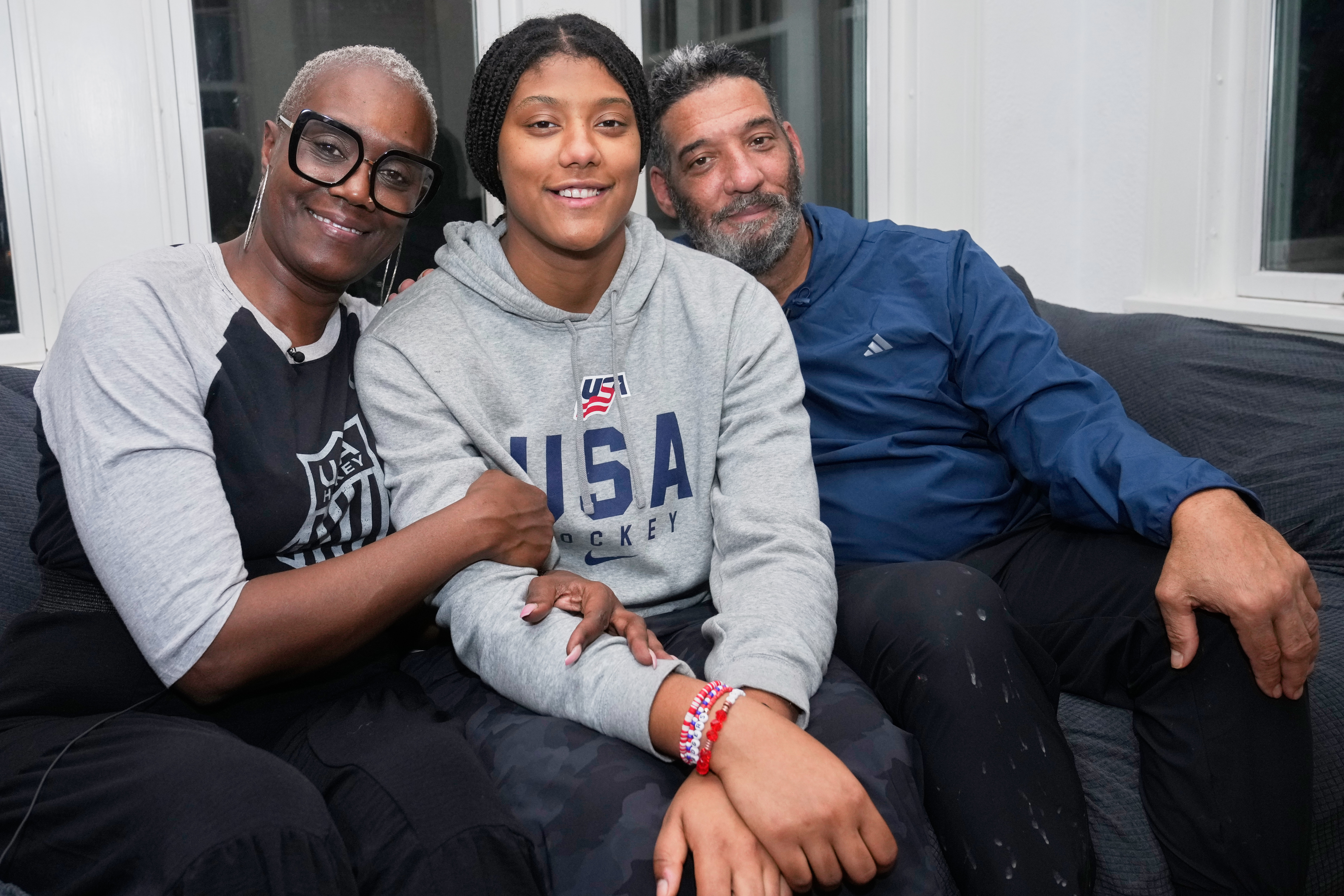 Laila Edwards, center, the first Black woman to suit up for Team USA women's Olympic hockey, poses for a photo with her parents, Charone Gray-Edwards, left, and Robert Edwards, right, in her childhood home in Cleveland Heights, Ohio, Wednesday, Nov. 5, 2025.