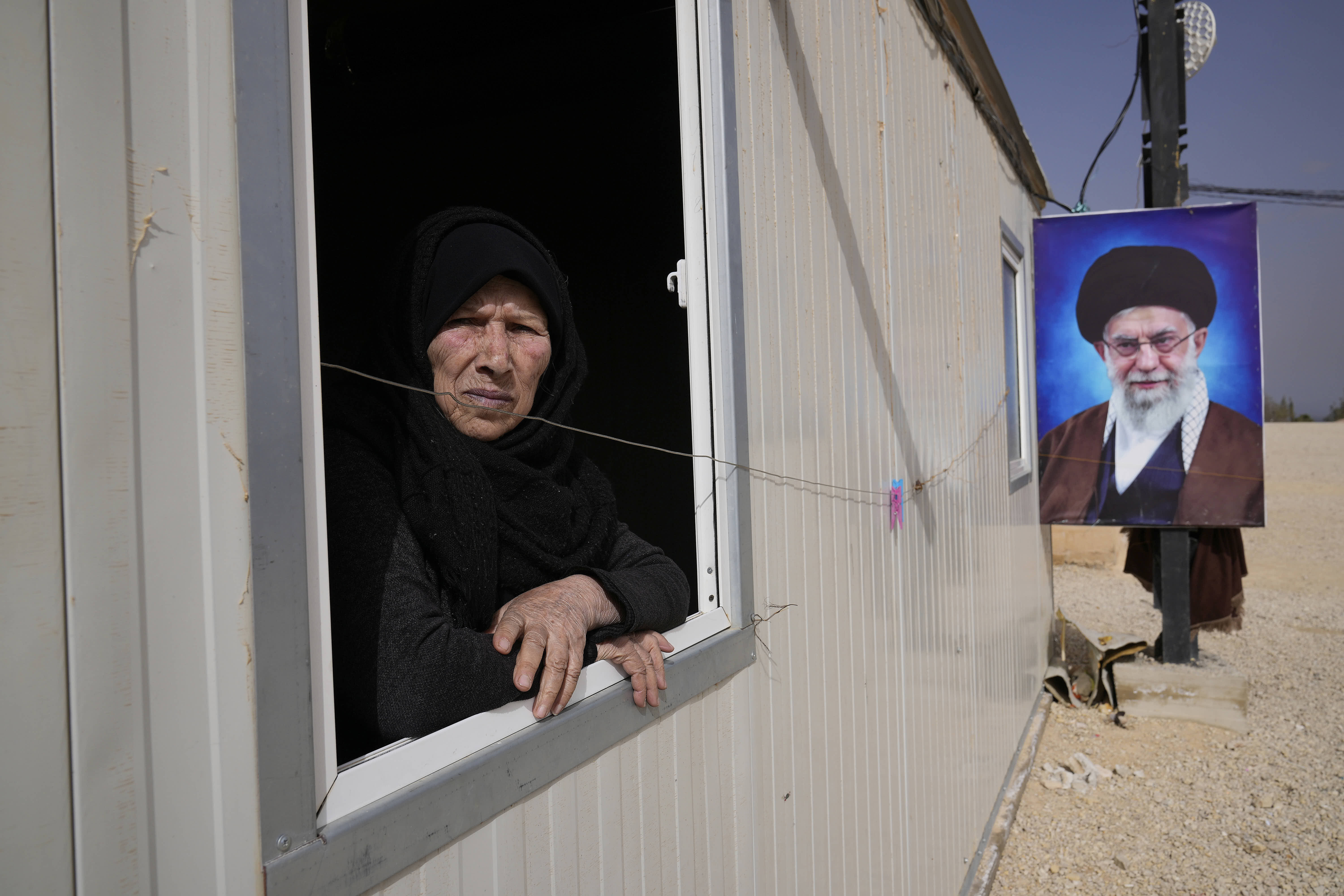 A displaced Syrian woman looks out from her new home in Hermel, Lebanon.
