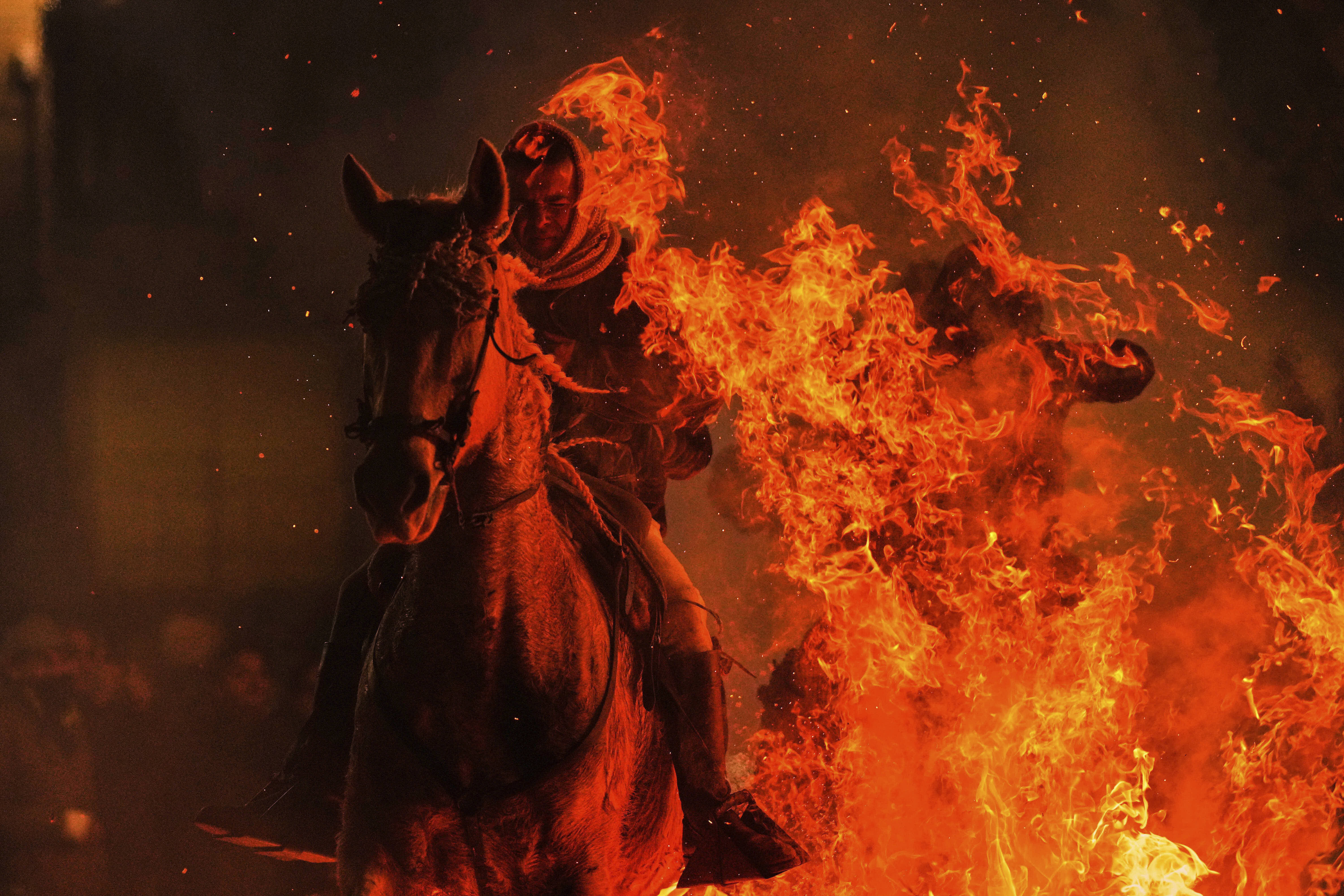 A man rides a horse through a bonfire in honor of Saint Anthony the Abbot in San Bartolome de Pinares, Spain. 