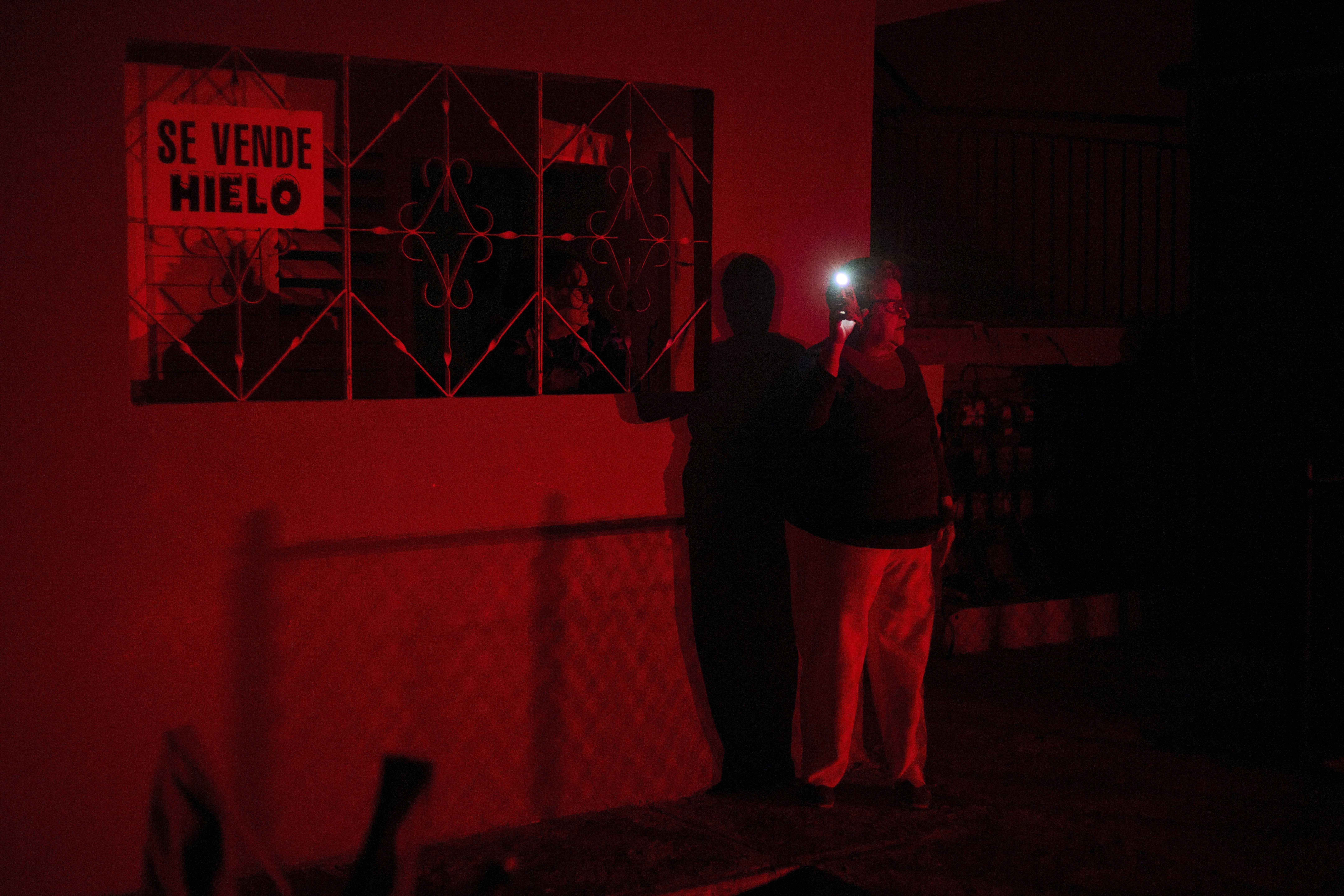 A woman holds up a cell phone flashlight during a scheduled power outage in Santa Cruz del Norte. 