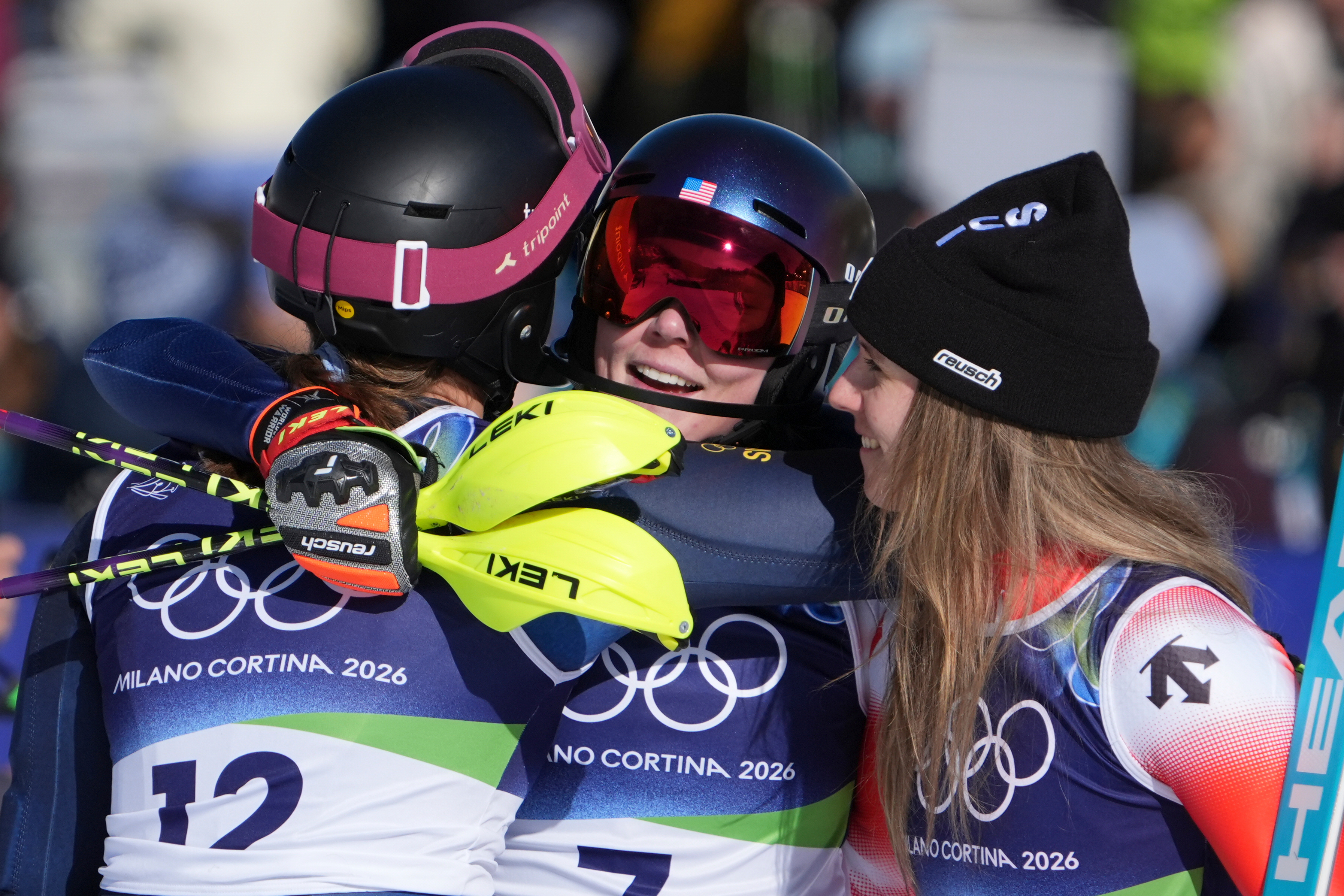 United States' Mikaela Shiffrin, center, winner of an alpine ski, women's slalom race, is congratulated by second-placed Switzerland's Camille Rast, right, and third-placed Sweden's Anna Swenn Larsson, at the 2026 Winter Olympics, in Cortina d'Ampezzo, Italy, Wednesday, Feb. 18, 2026.