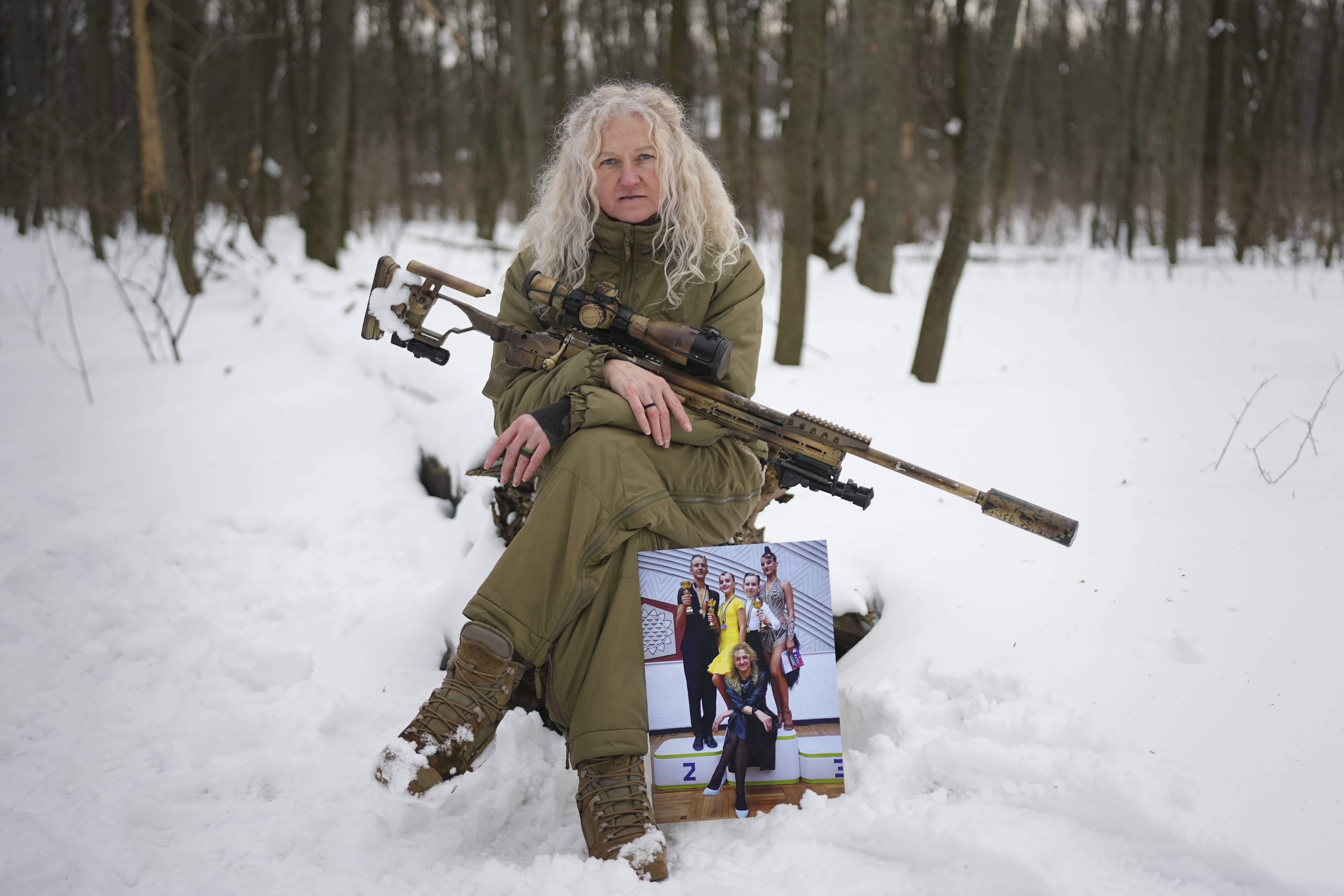 Ukrainian Army sniper Tetiana Khimion poses with a photograph of herself as a dance teacher taken before Russia's full-scale invasion, in Kyiv.