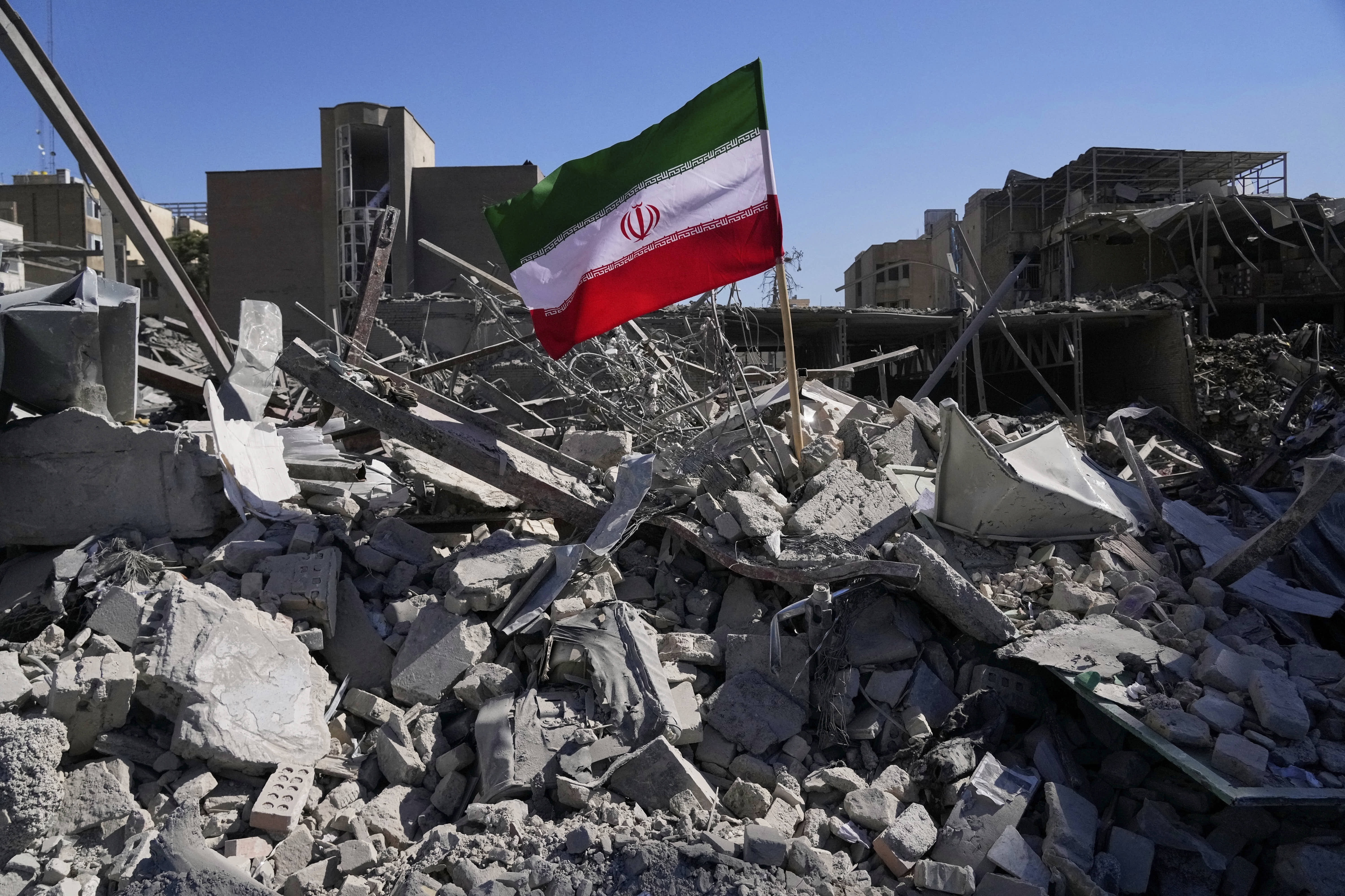 An Iranian national flag is planted in the rubble of a police station struck during a US-Israeli military campaign in Tehran. 