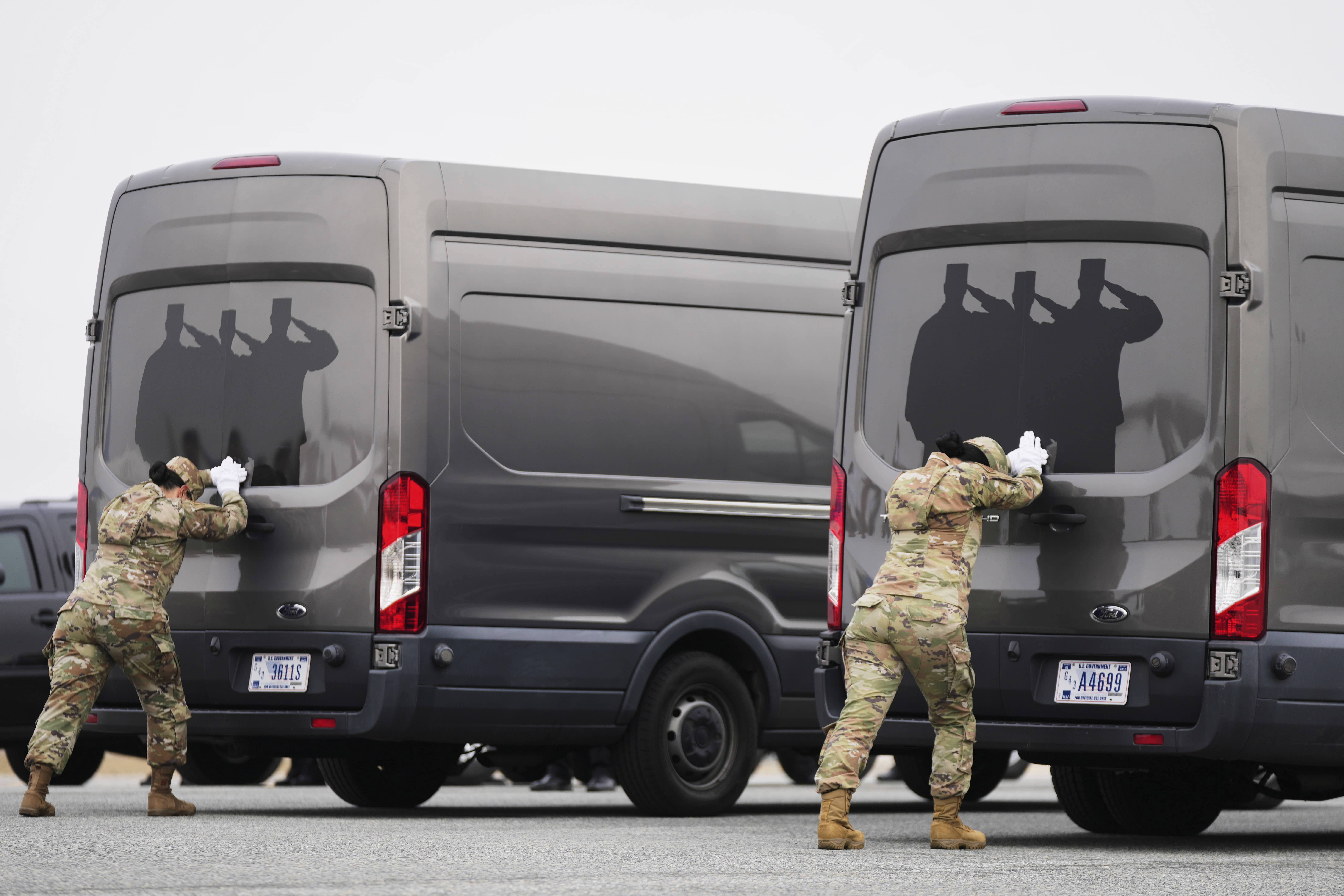 Airmen secure the doors of transfer vans containing the remains of 6 soldiers killed in the war in the Middle East.