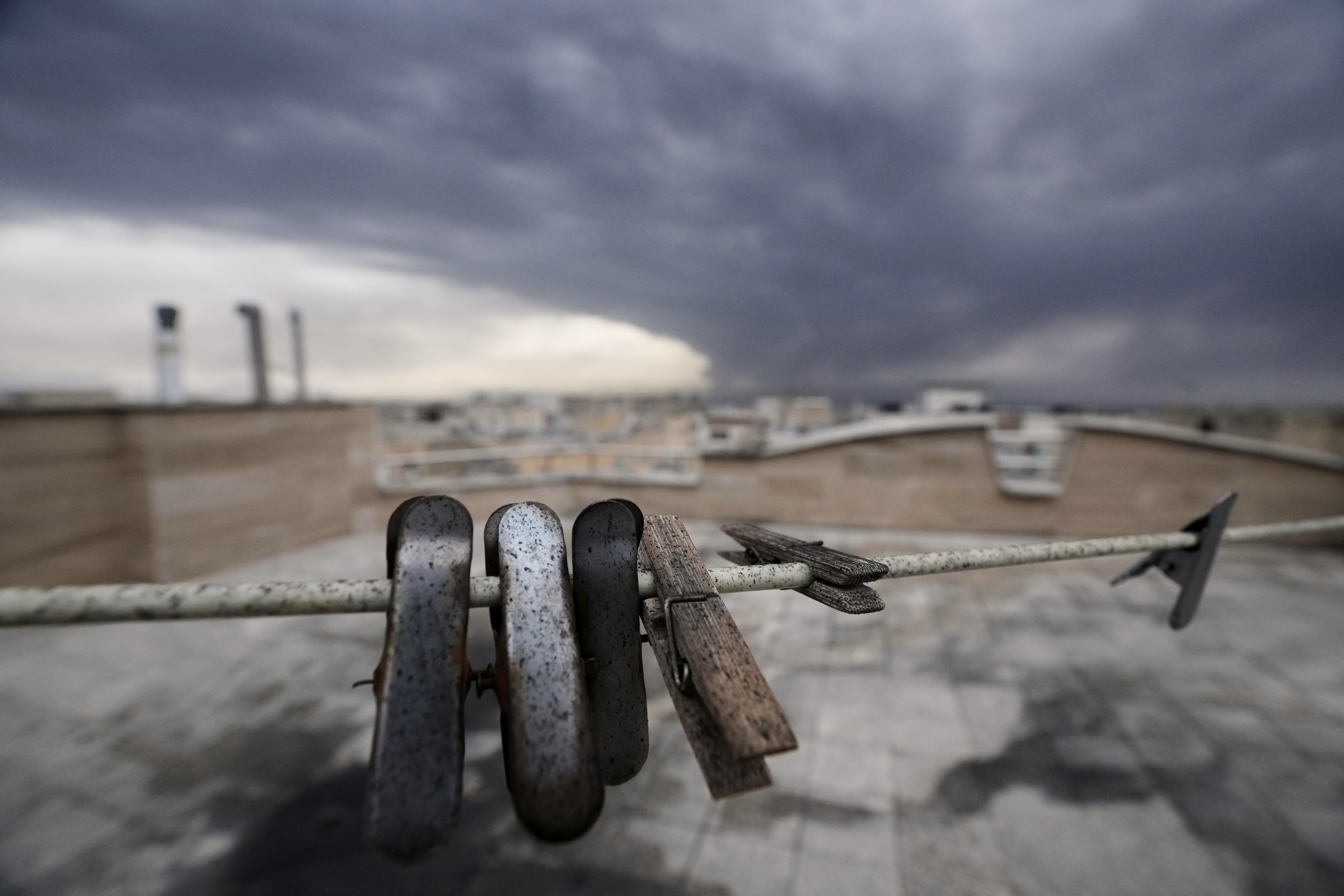 Soot-covered clothespins hang on a line as smoke from a U.S.-Israeli strike on an oil facility lingers over Tehran.