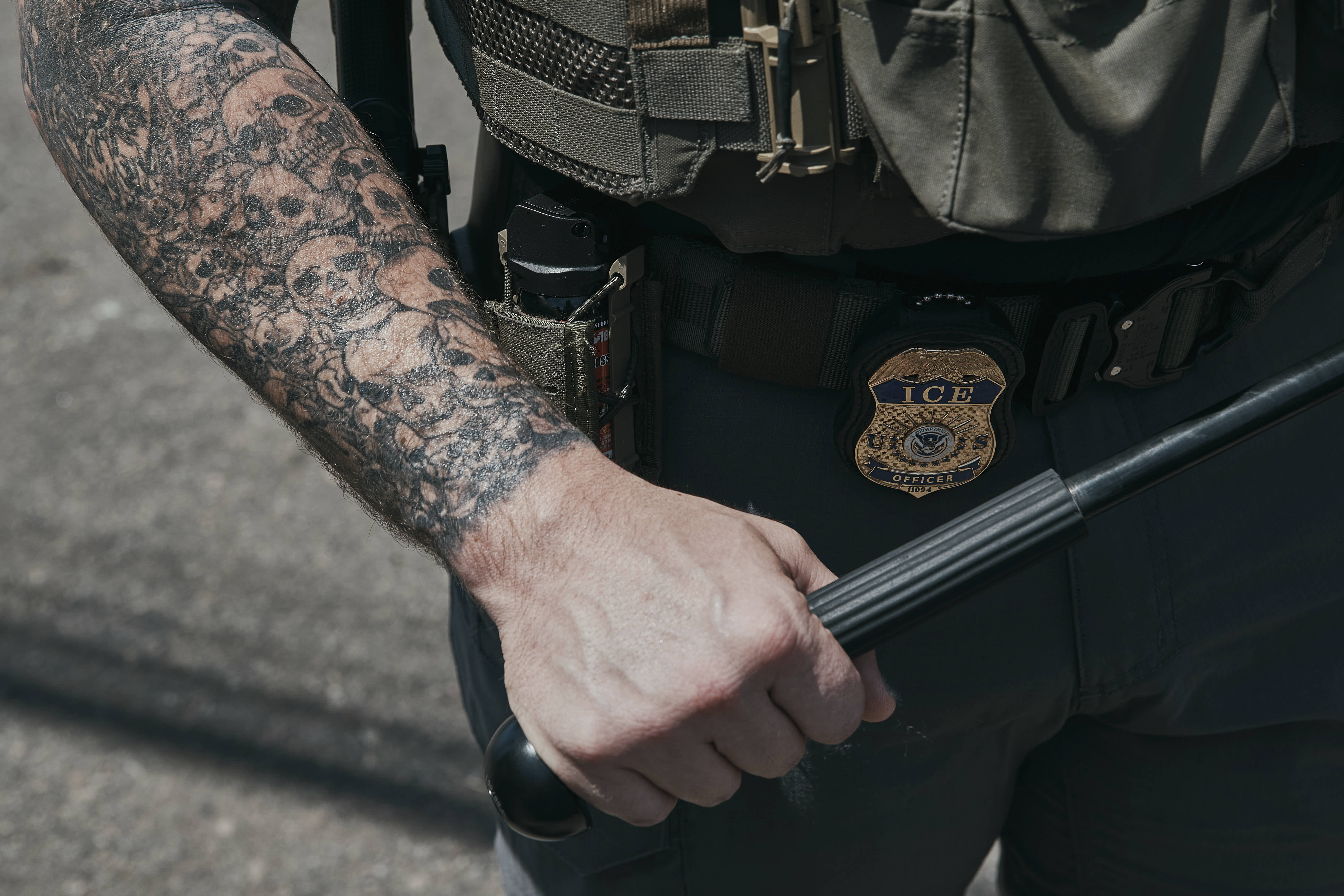 An ICE agent holds a baton during a protest outside a detention facility in Newark.