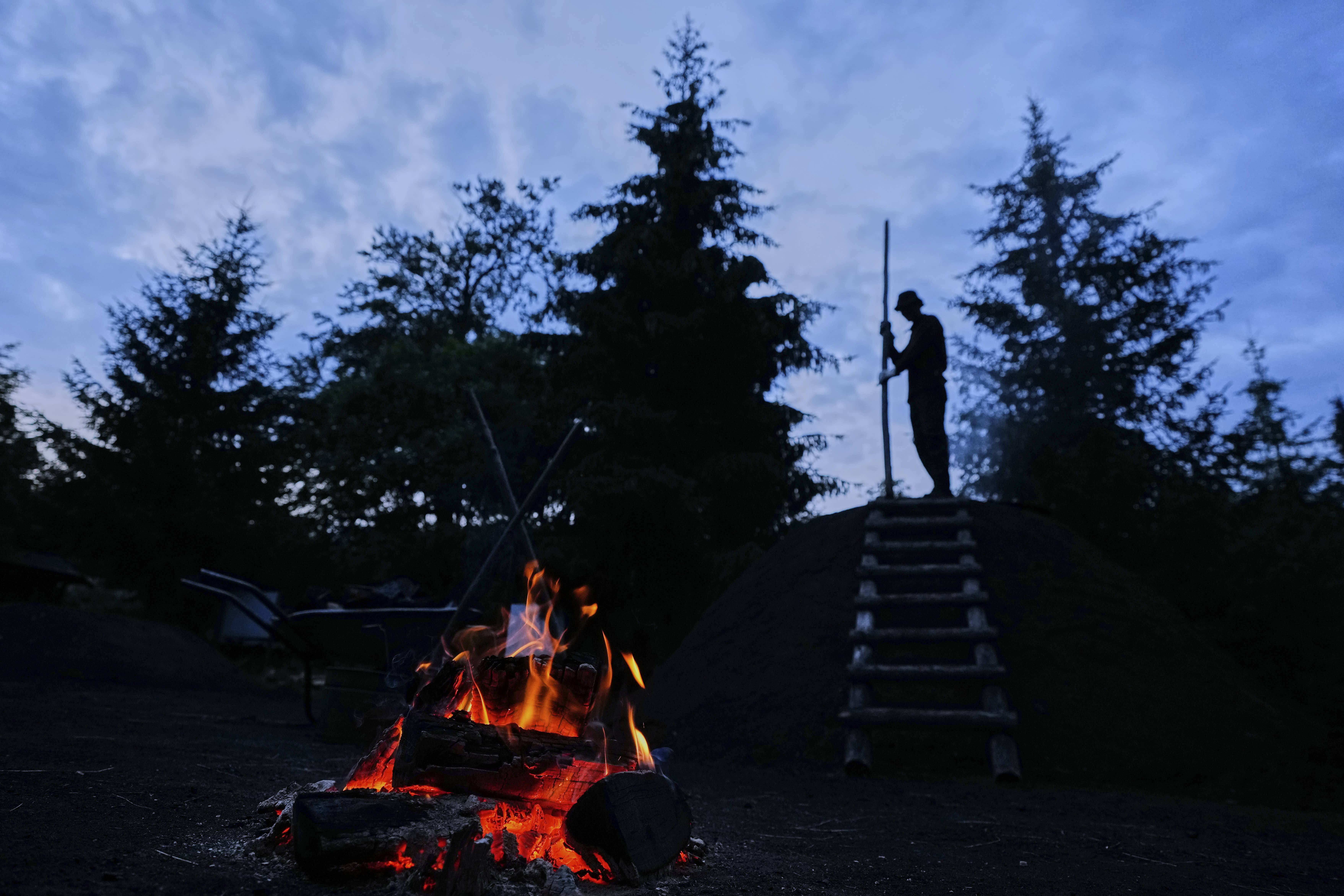 Immo Feldmer monitors the smoldering process at a traditional charcoal production site in Germany's Harz forest. 