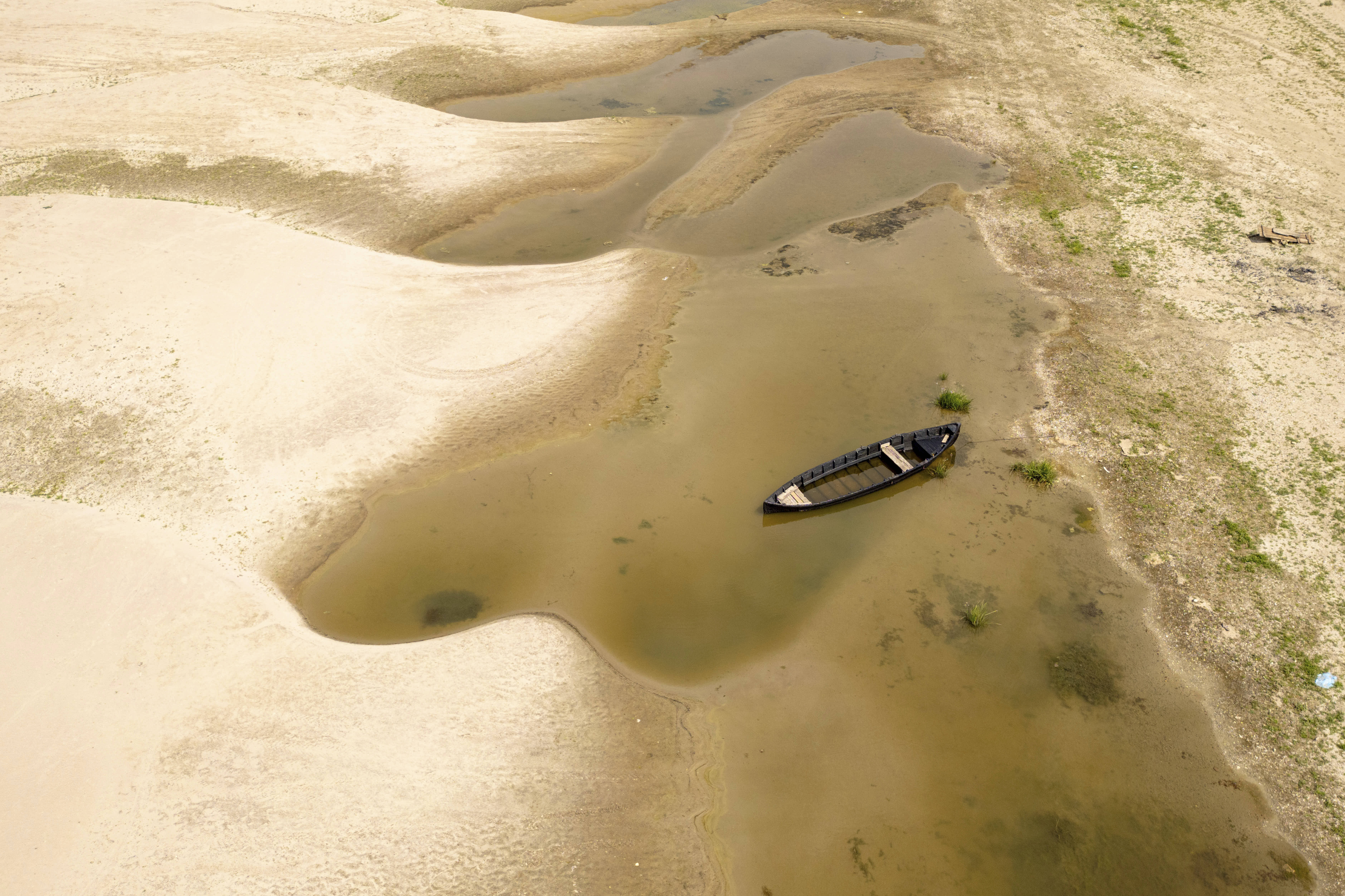 A boat sits in a pool of water on the exposed bed of the Danube River as water levels remain low. 