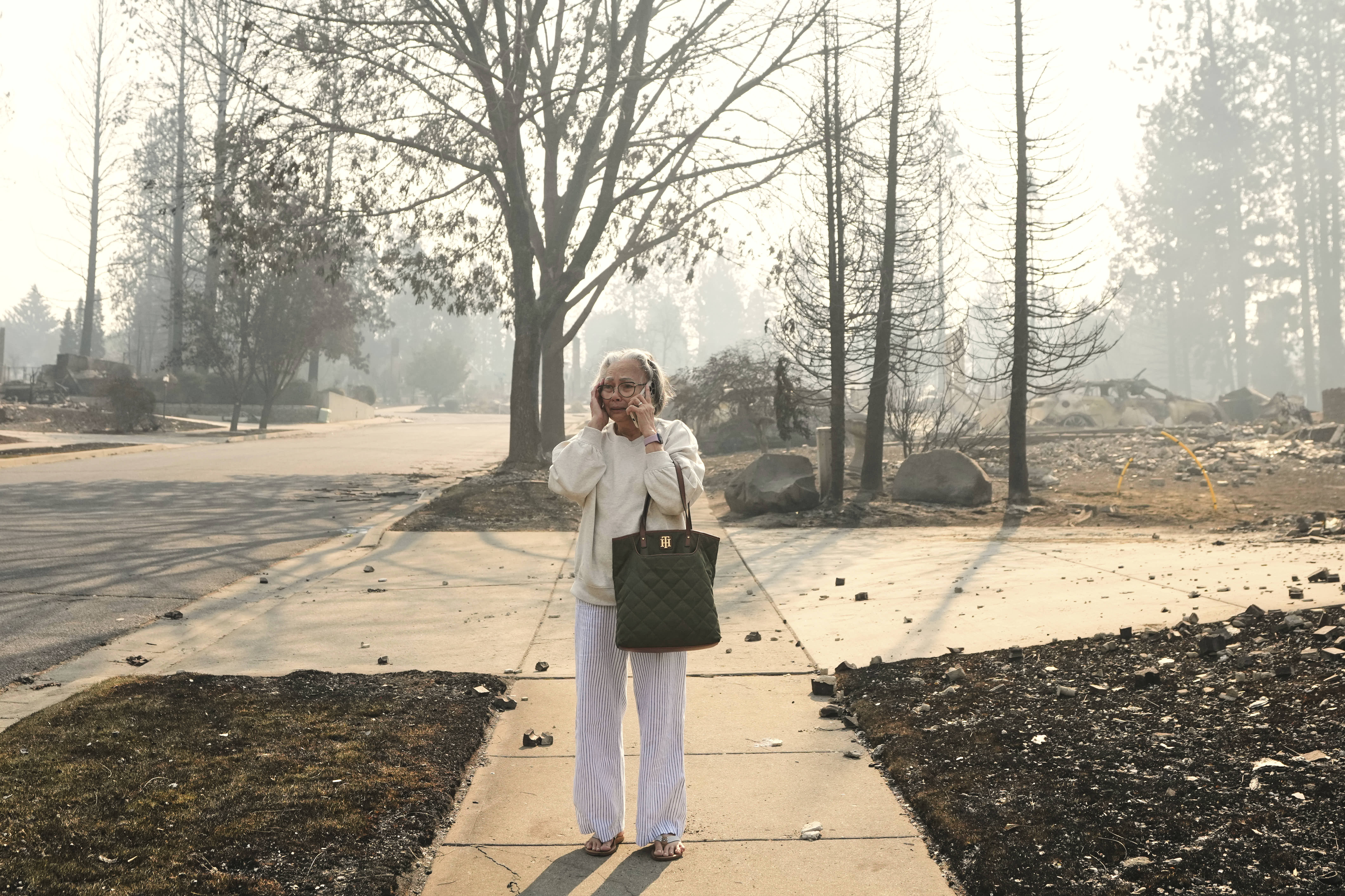 Miriam Sim stands amid the burned remains of her neighborhood after a wildfire in Spokane. 