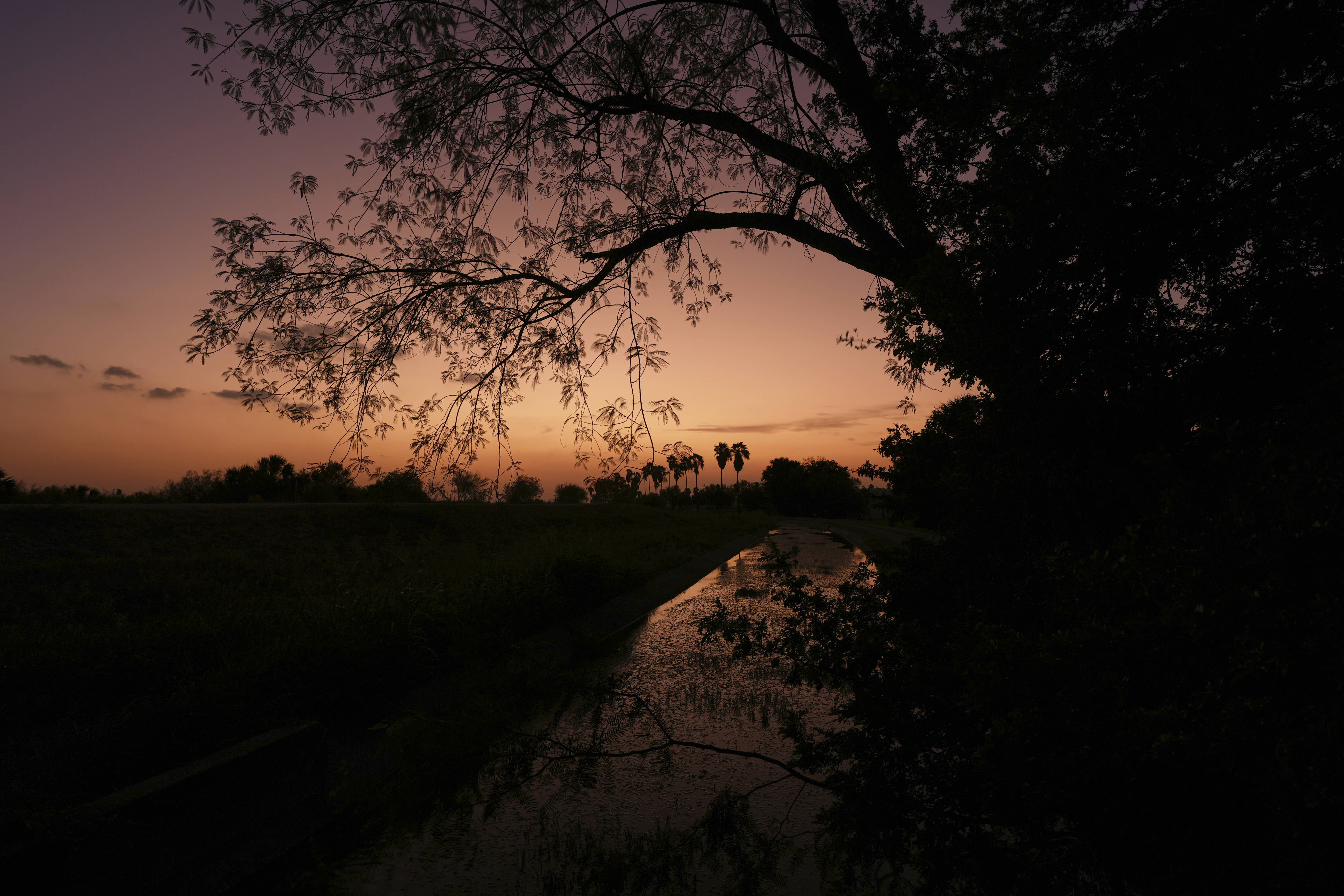 The sun sets over a levee at the Santa Ana Wildlife Refuge in Alamo, Texas. 