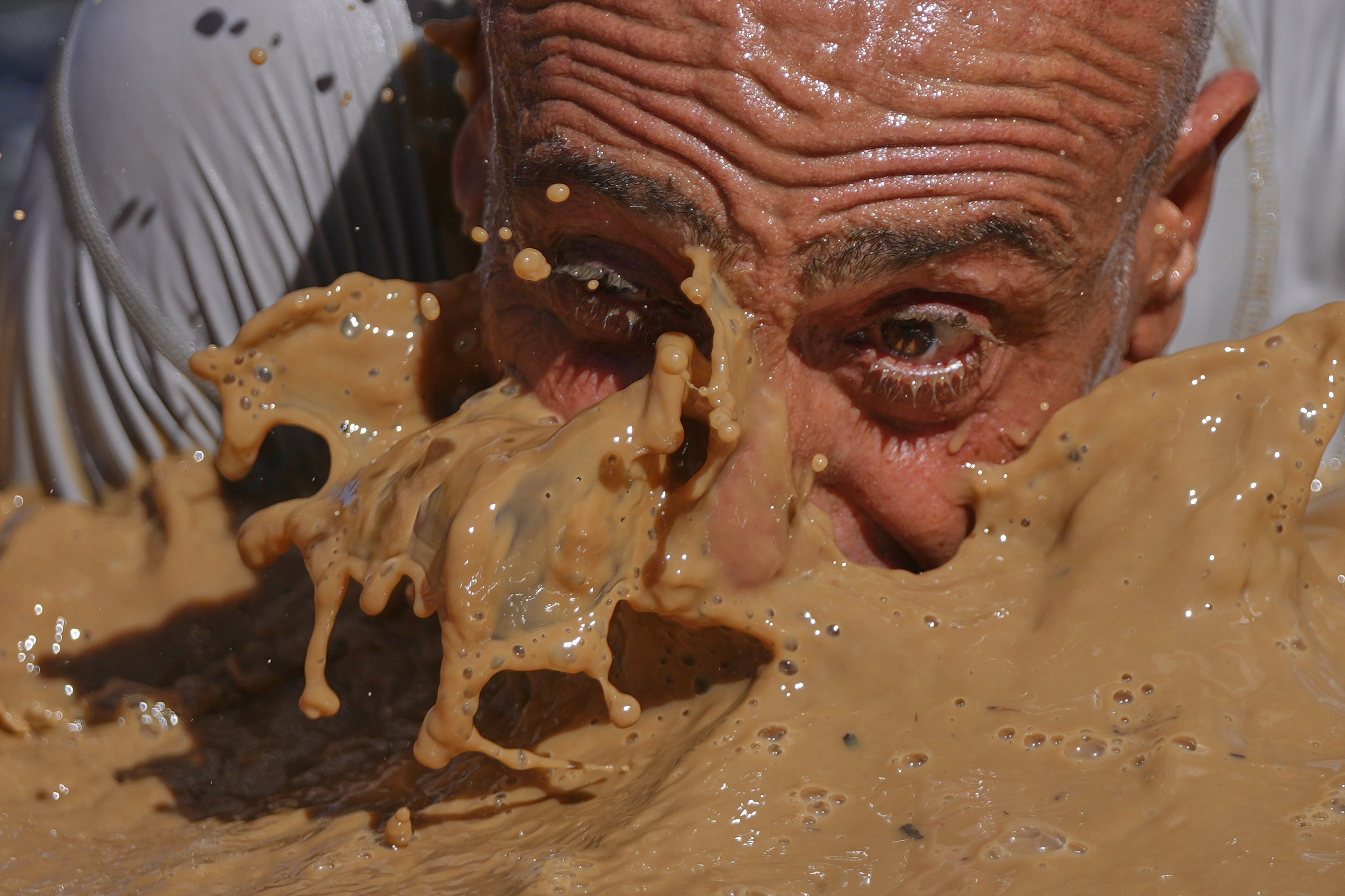 A competitor crawls through mud.