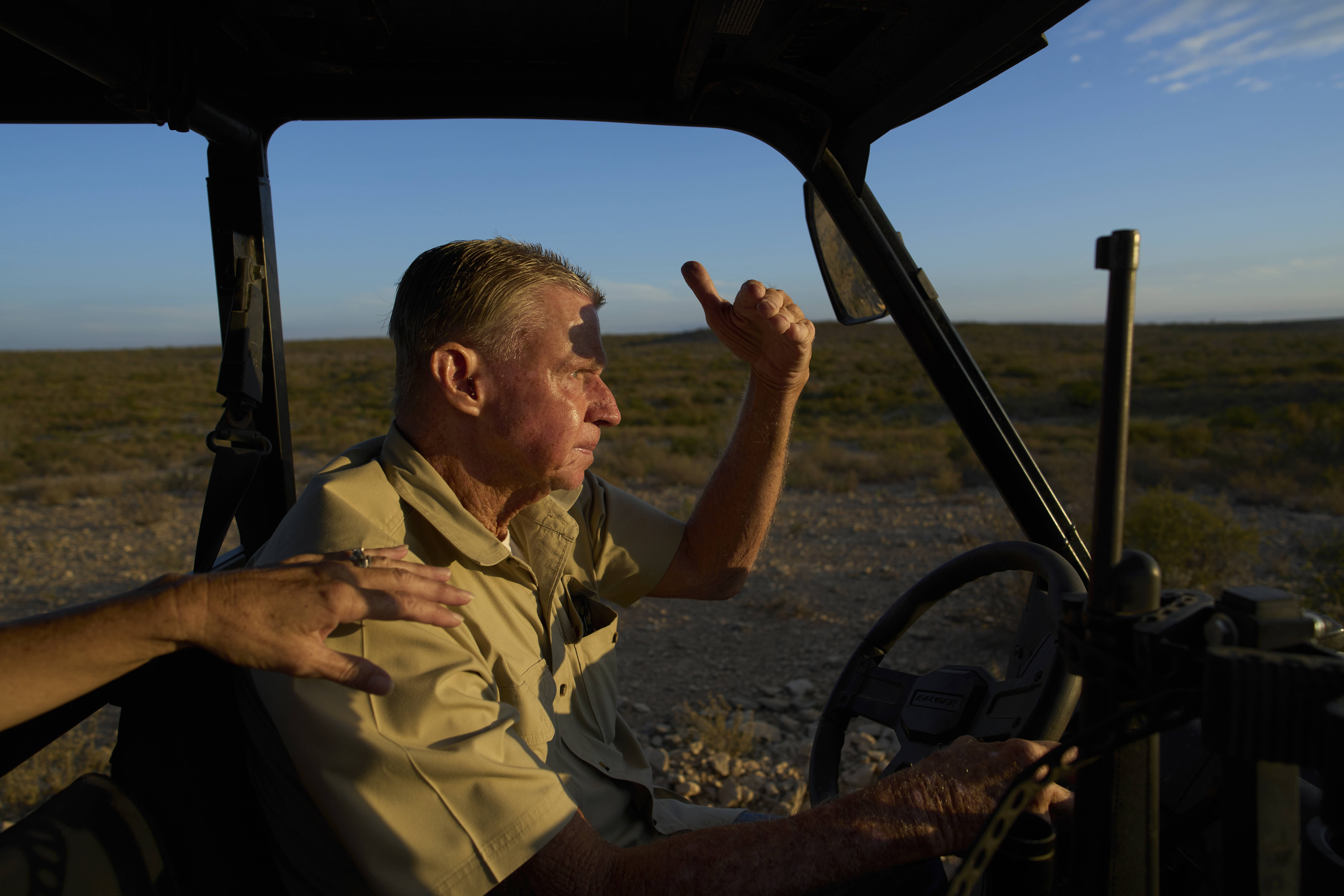 Lauren Allen rests her hand on her husband’s shoulder as he drives across their ranch in Comstock, Texas. 