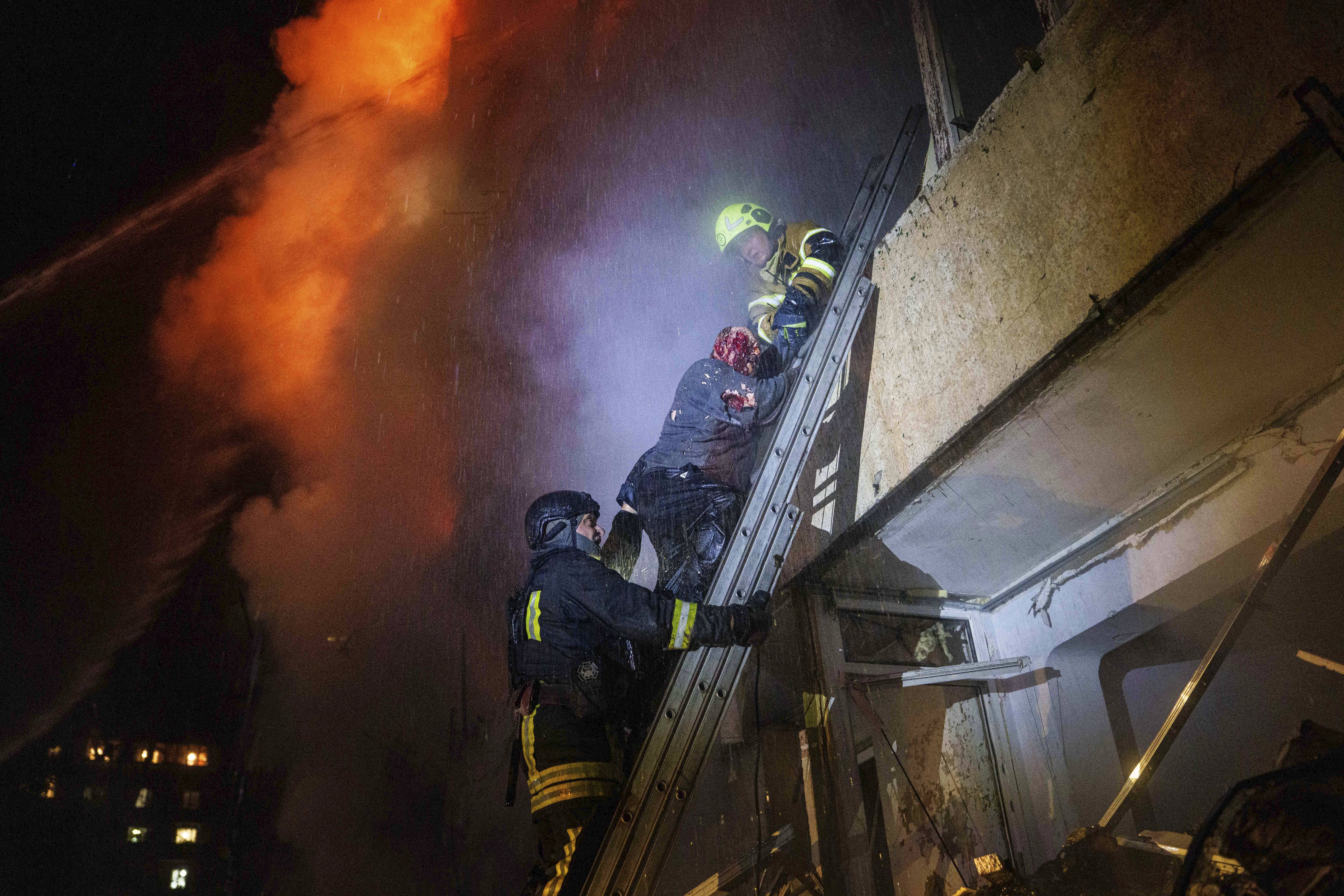 Rescue workers help a resident down a ladder from a residential building damaged by a Russian missile strike in Kyiv. 