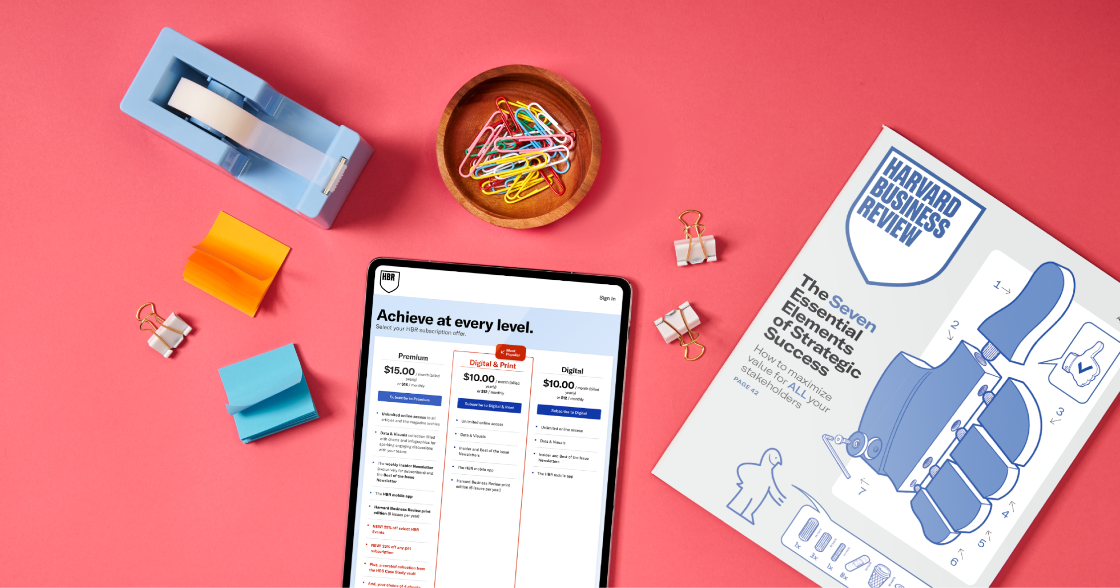 An issue of HBR and various office supplies next to a tablet showing the HBR subscriptions webpage.