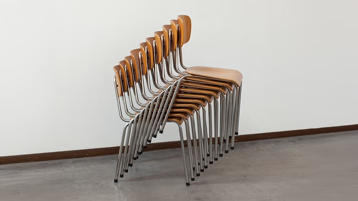 Photo of a bunch of classroom chairs stacked up on each other.