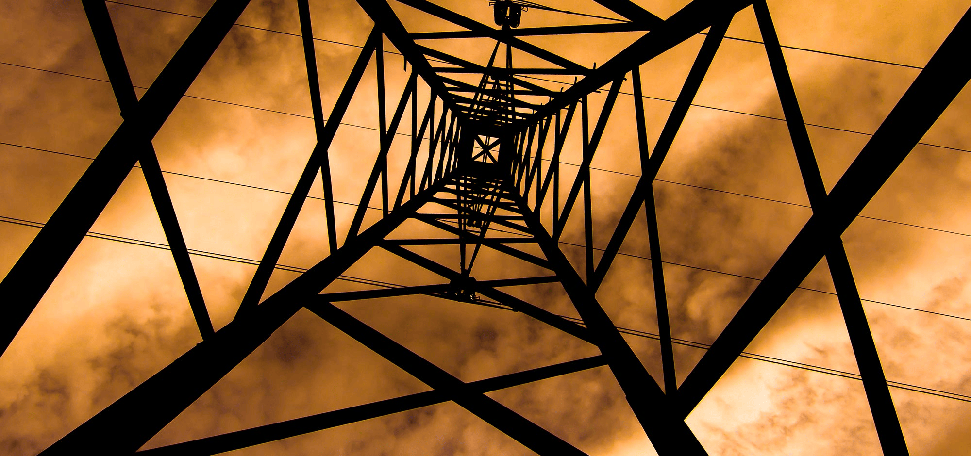 Silhouette of a metal tower structure against an orange sky.