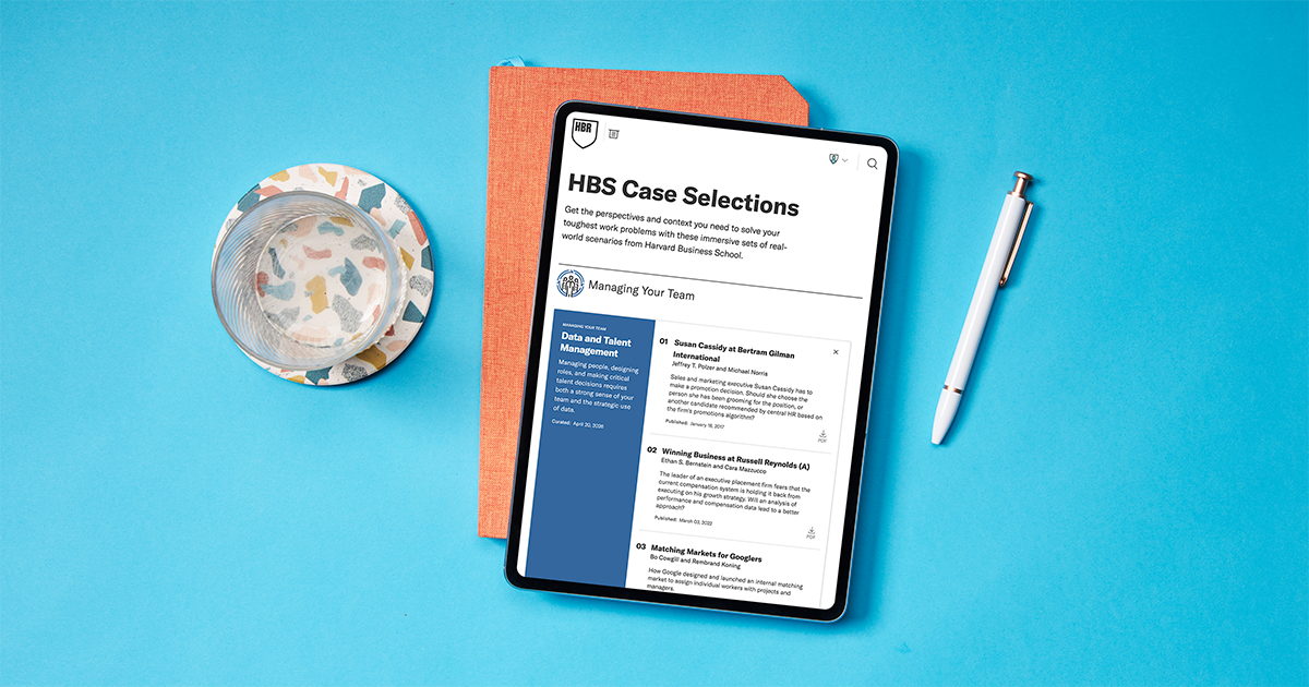 Tablet showing HBS Case Selections from Harvard Business School, featuring a collection of case studies on managing data and talent. The tablet rests on an orange notebook beside a pen and glass of water on a blue background.