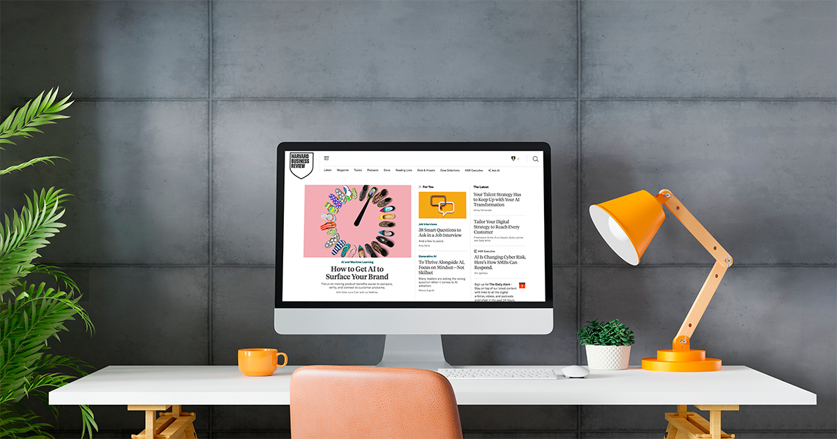 A tablet displaying a Harvard Business Review article titled Gen AI Won't Make Your Employees Experts surrounded by office supplies on a pink background.