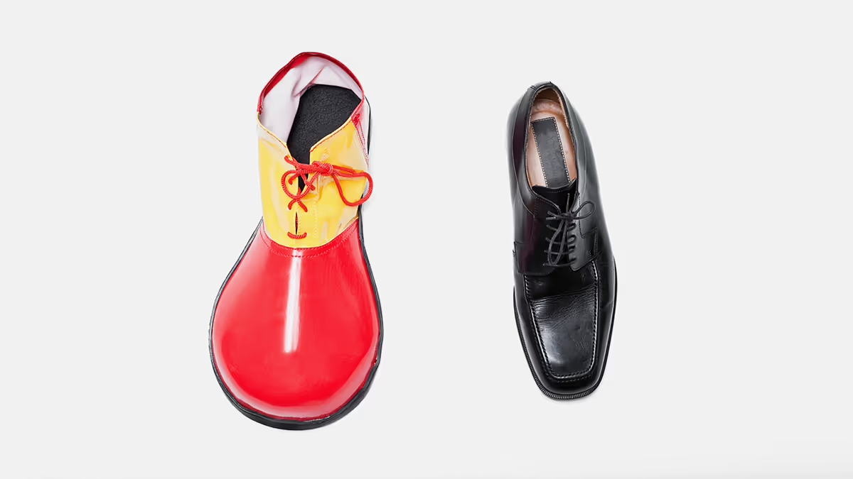 A clown shoe next to a regular black shoe.