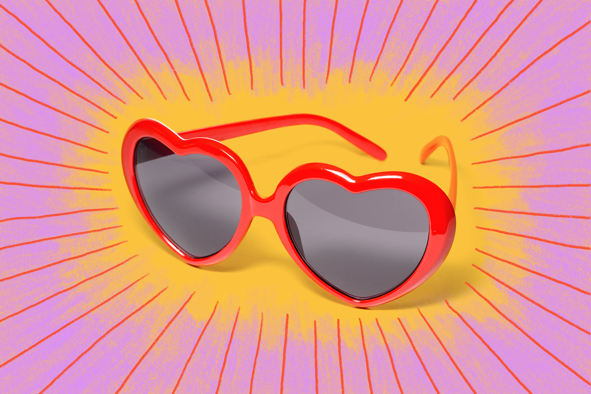 A pair of red, heart-shaped sunglasses on a pink and yellow background.