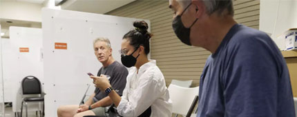Three patients wait to be vaccinated at a clinic.