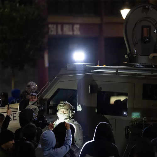 ICE officers try to leave the scene while protesters stand nearby in the dark. ICE officers try to leave the scene while protesters stand nearby in the dark.