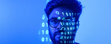 A man stands under blue light with numbers projected on his face like 'The Matrix.'